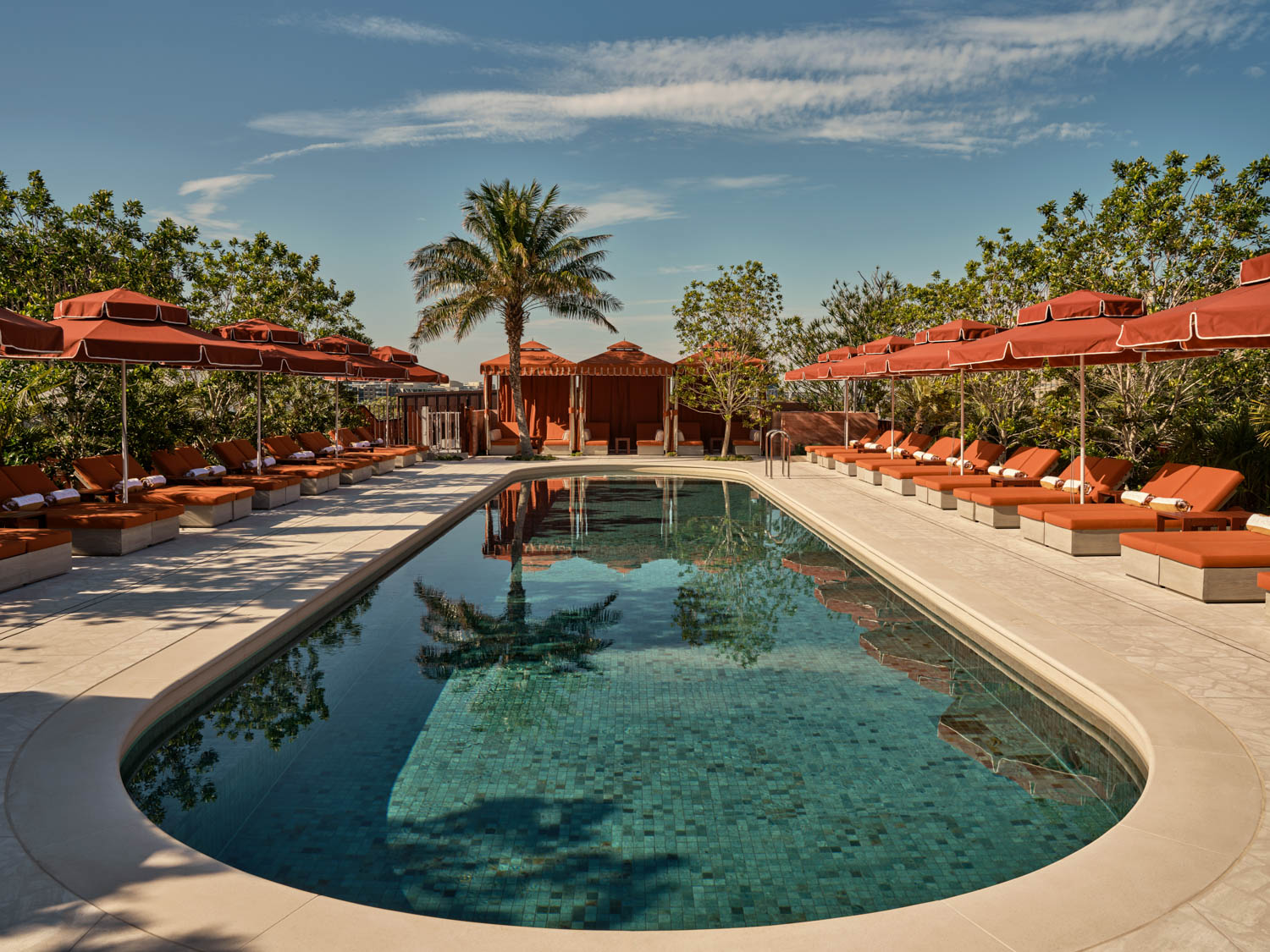 pool with orange umbrellas and cabanas