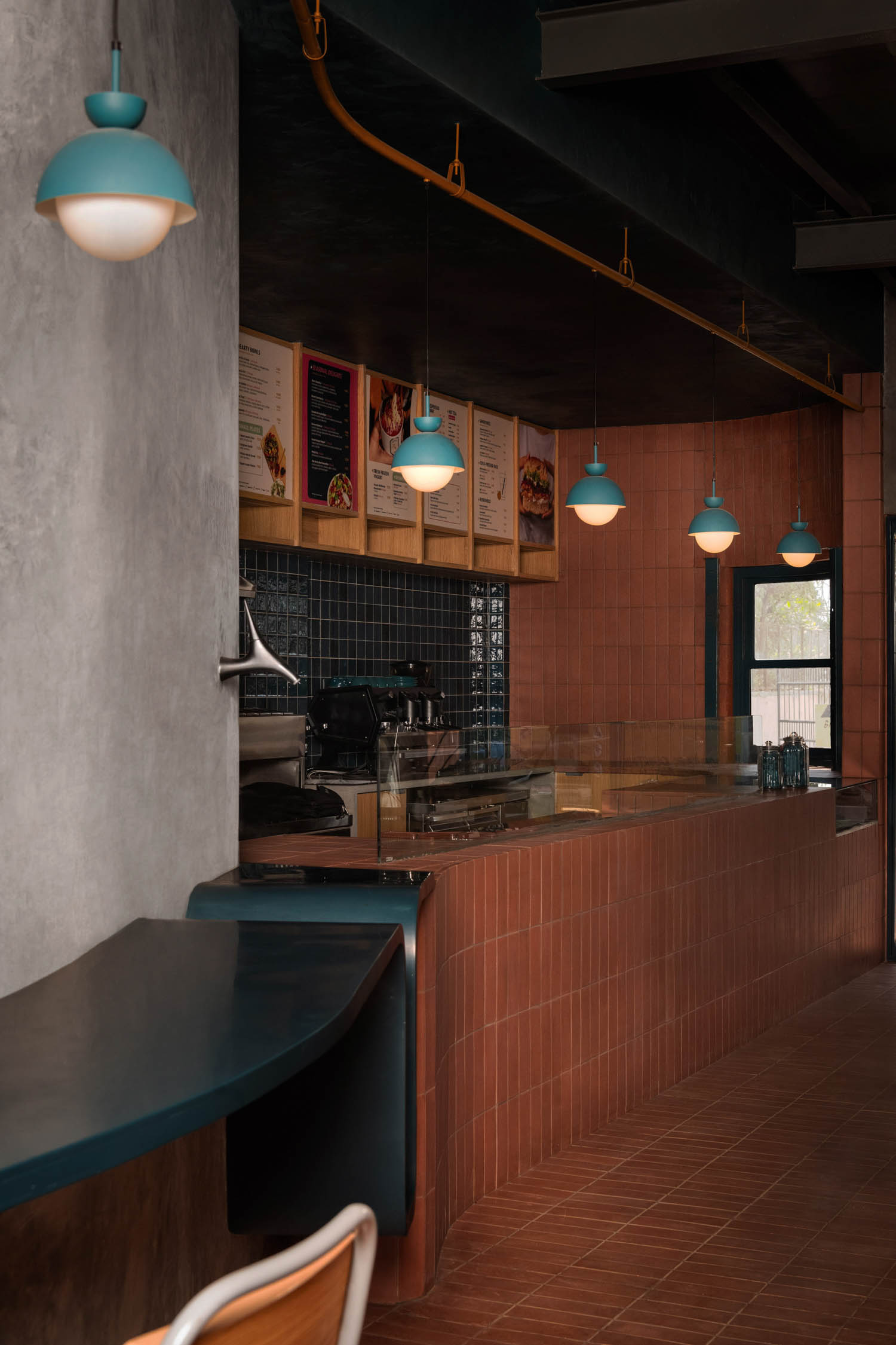 the cafe design includes a community work table with hanging pendant lights overhead