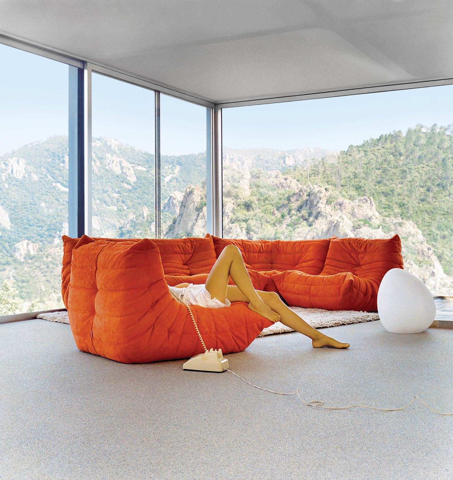 person sitting on an orange couch but only seen with legs