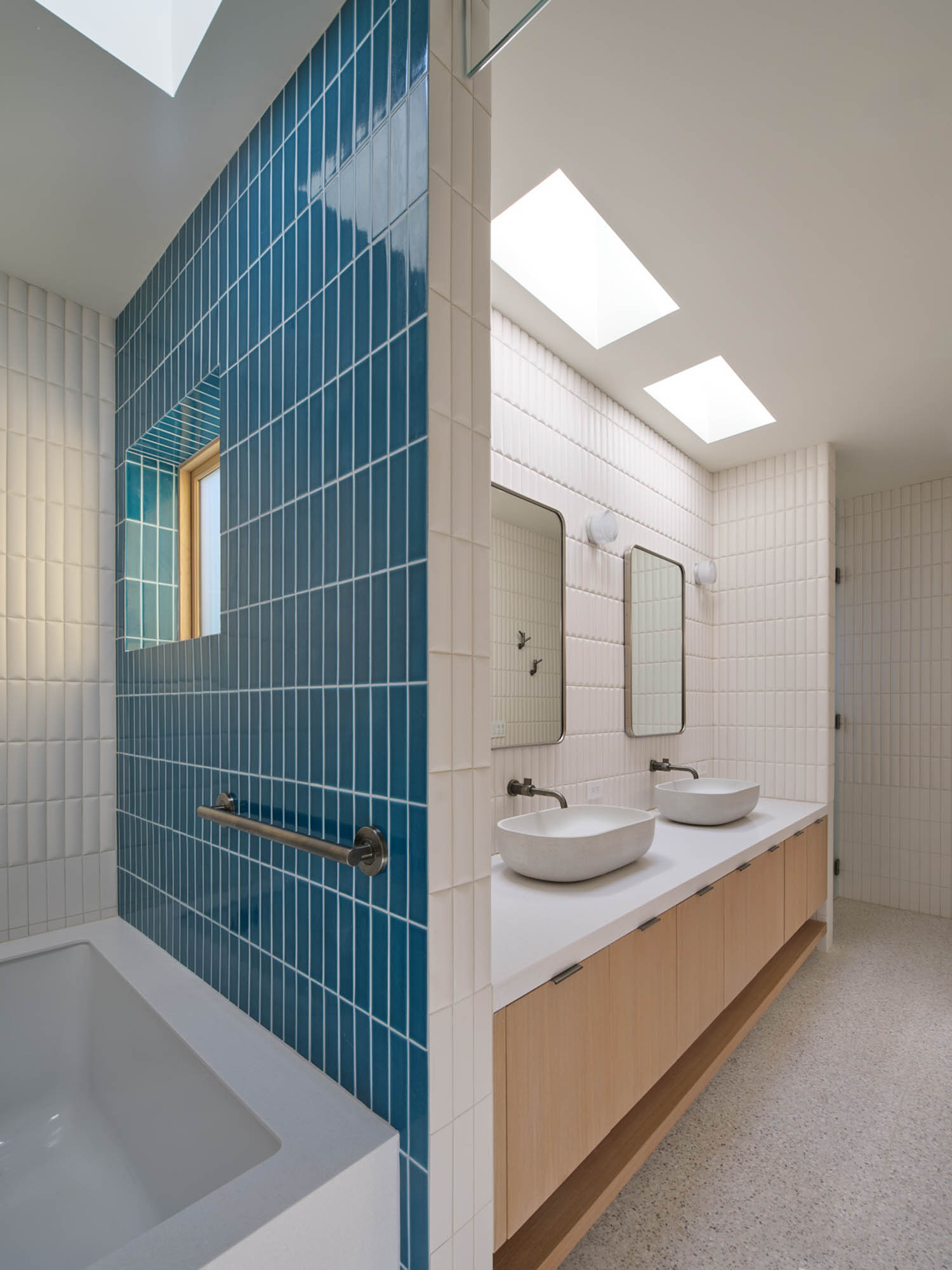 bathroom with blue tile surrounding tub and sinks