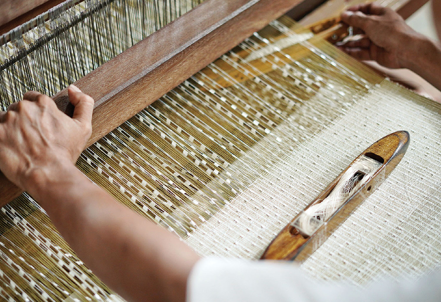 A woman is weaving a piece of fabric on a loy.