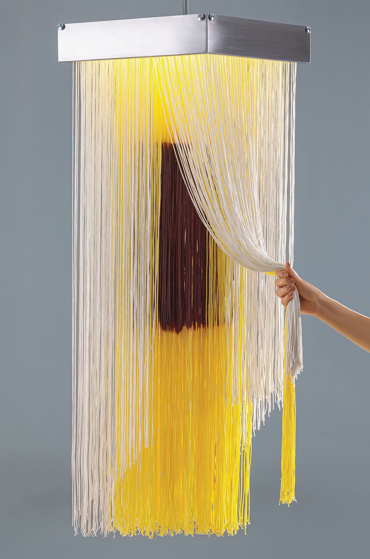 A woman is holding a light fixture with spaghetti.