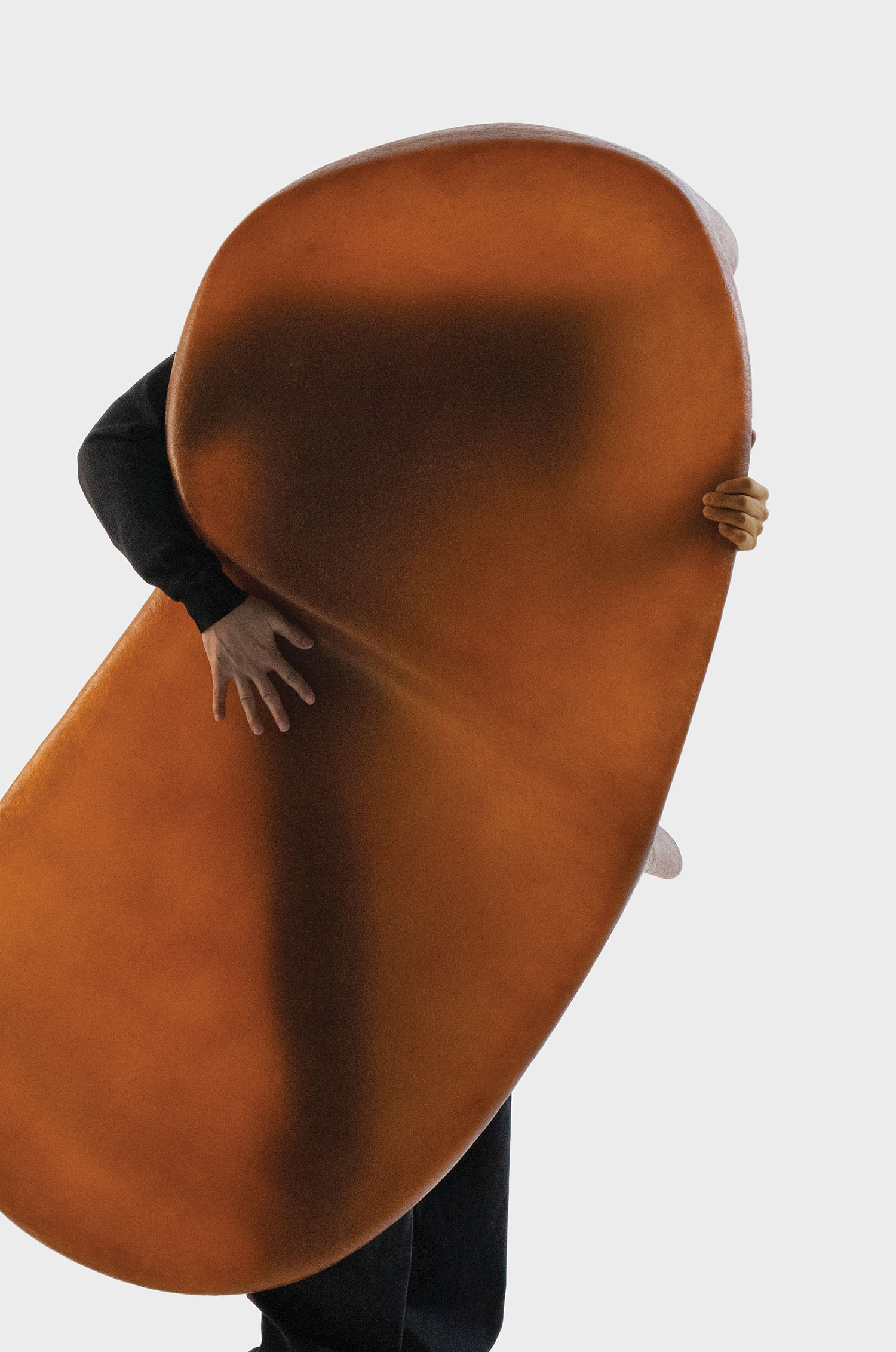 A man in a suit holding a large orange object.