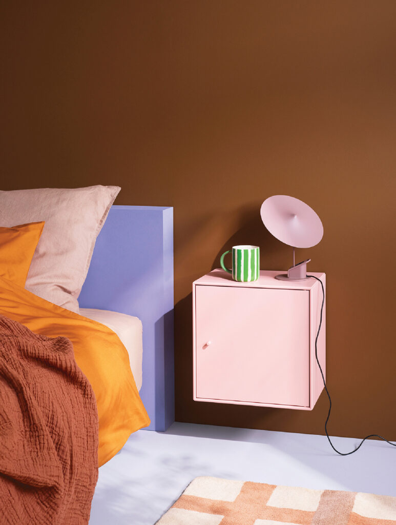 A pink nightstand with a green lamp on top.