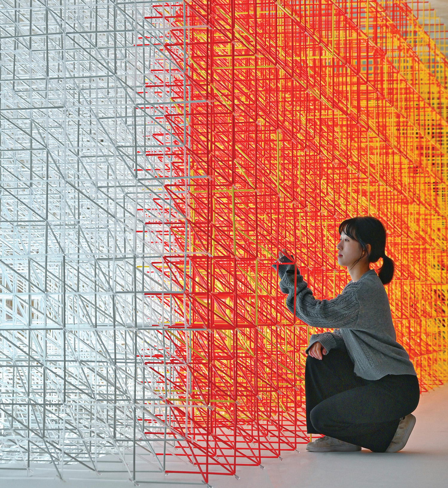 A woman kneeling in front of a large red and yellow structure.
