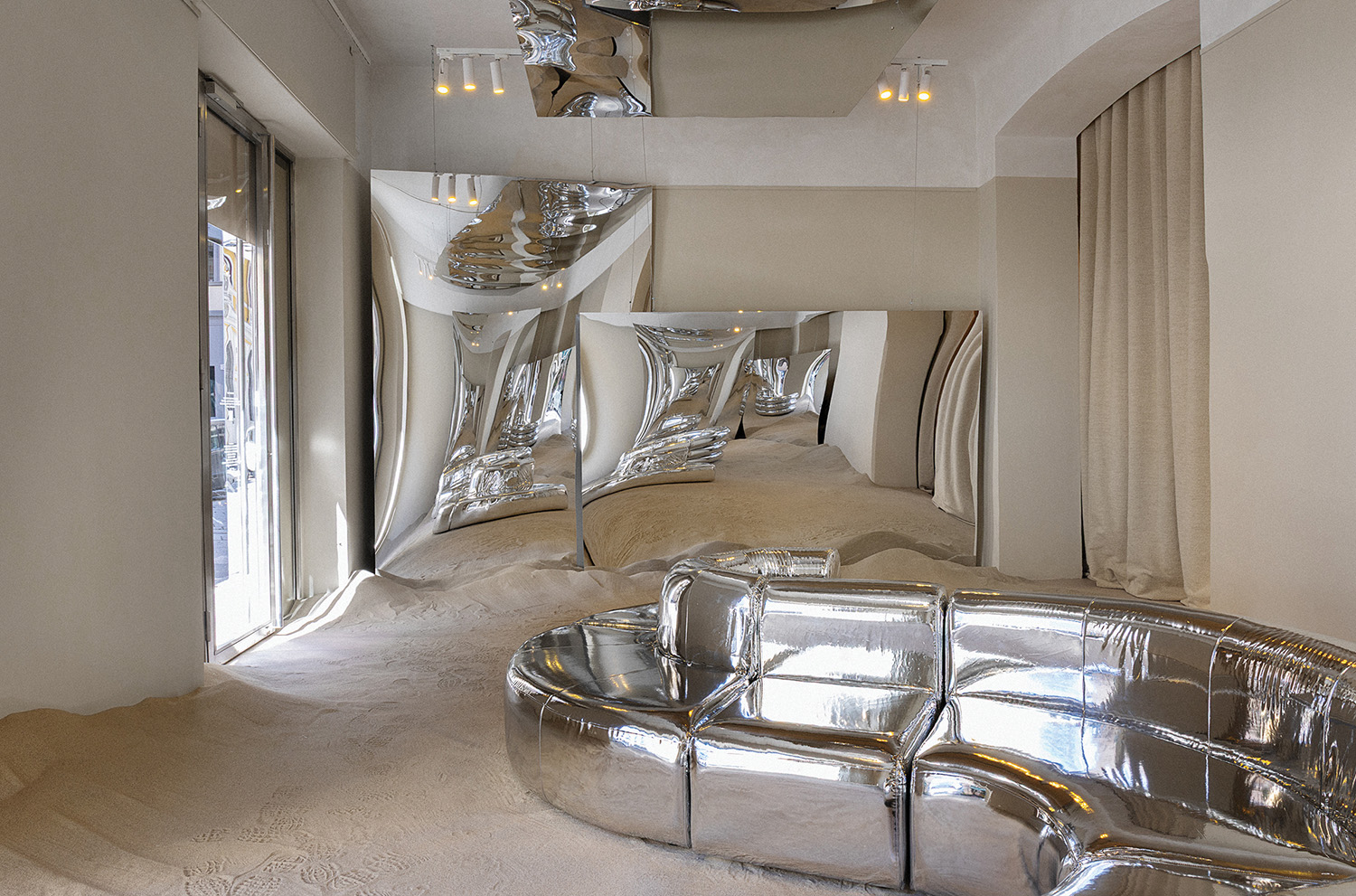 A mirror room with a shiny silver couch.