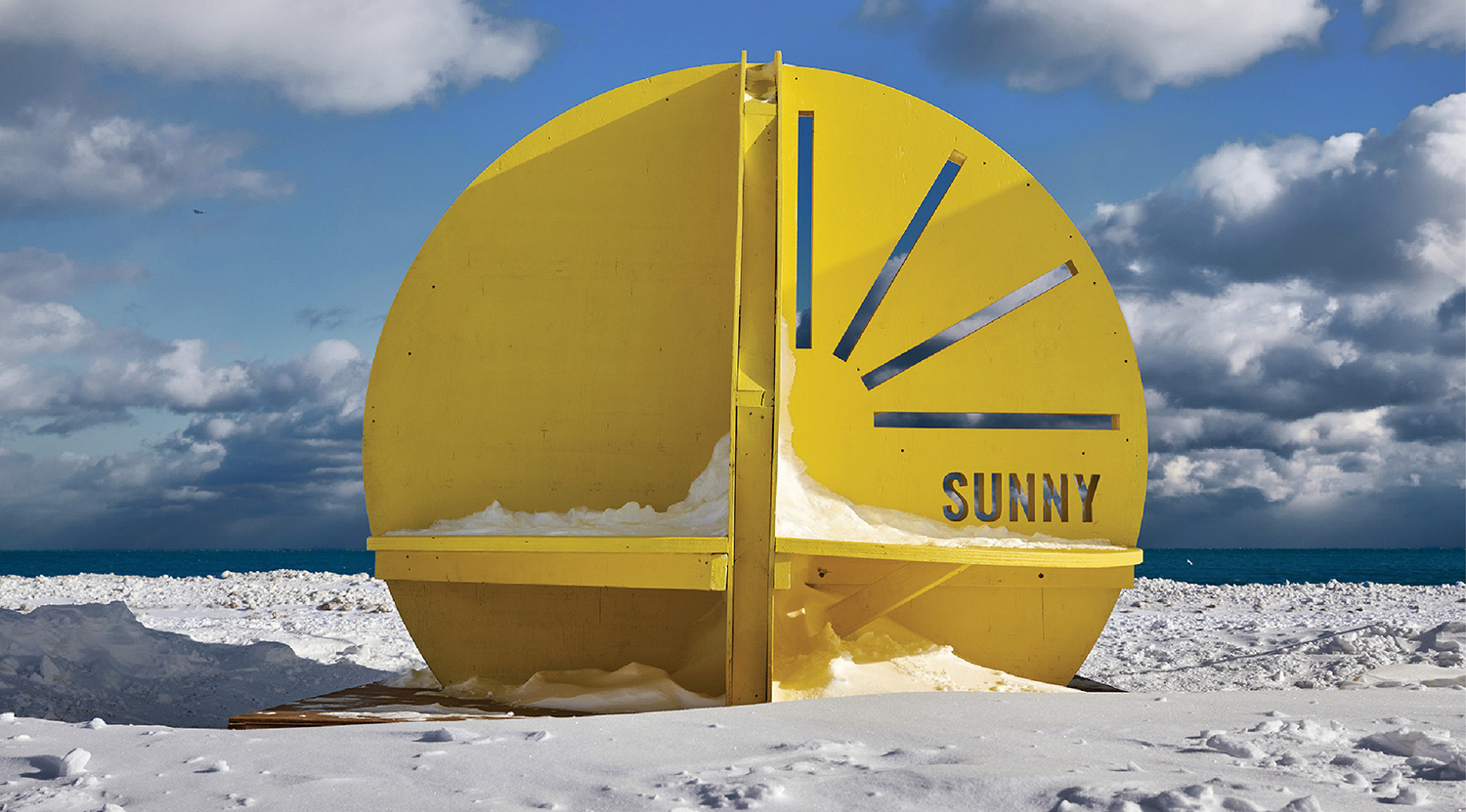 A yellow clock on the beach.