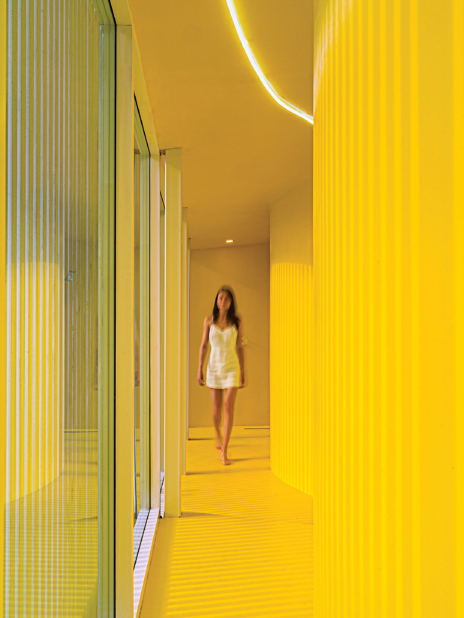 A woman walking down a yellow hallway.