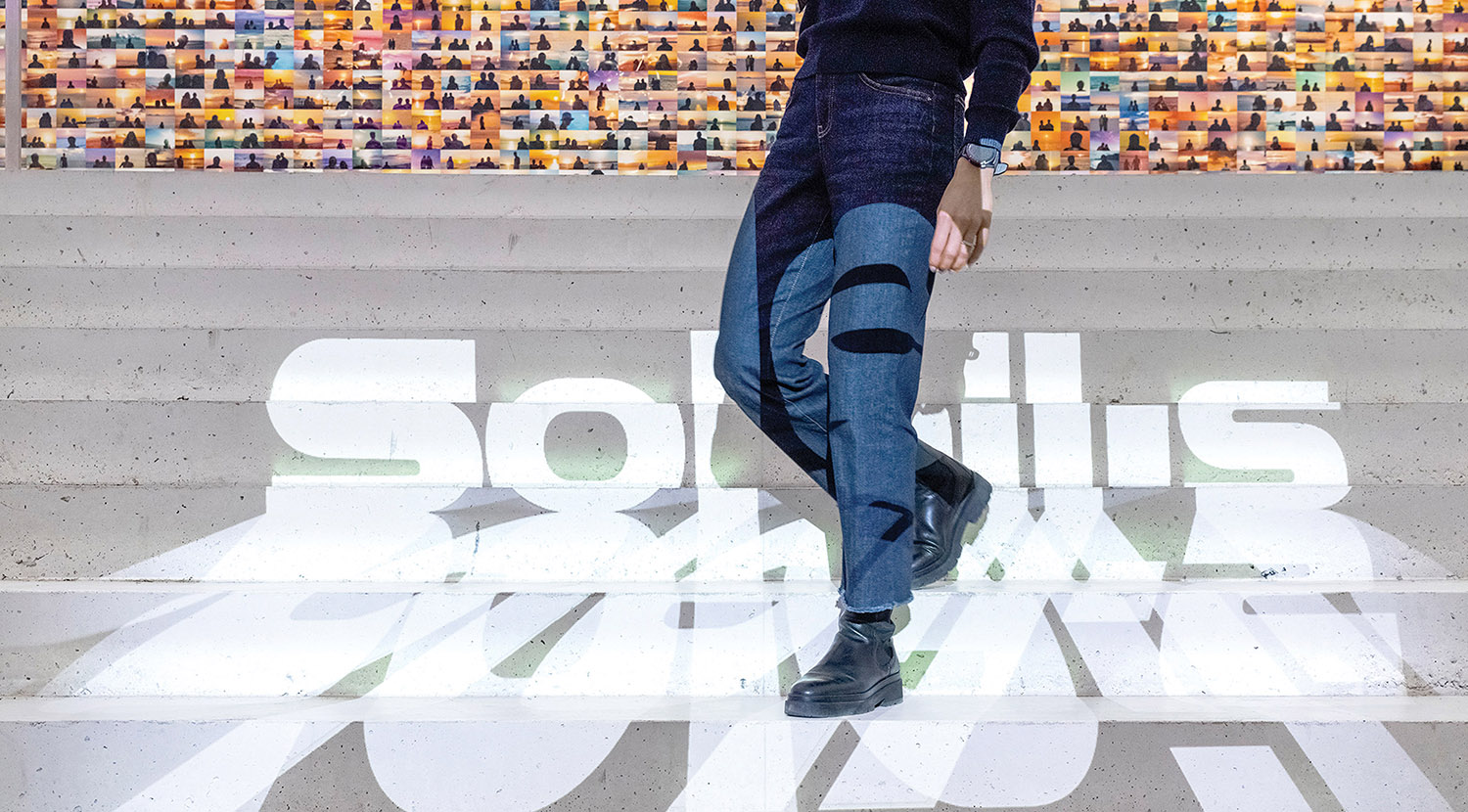 A man standing on a white floor with a wall of people.