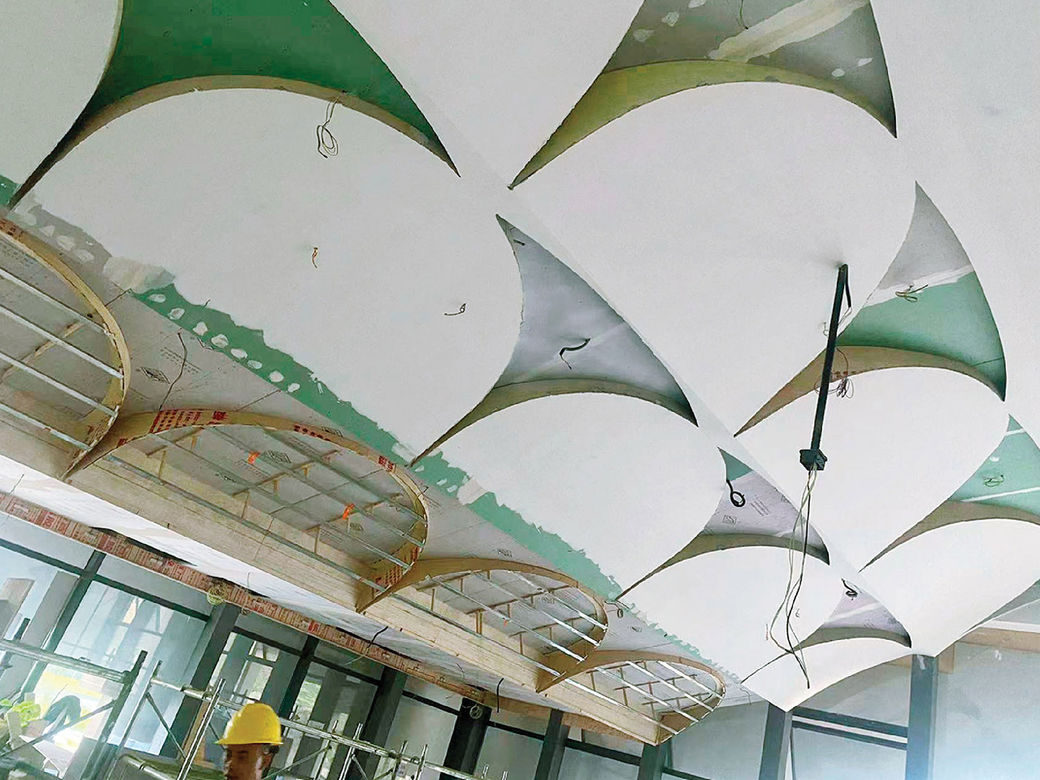 A man is working on a ceiling with a clock.