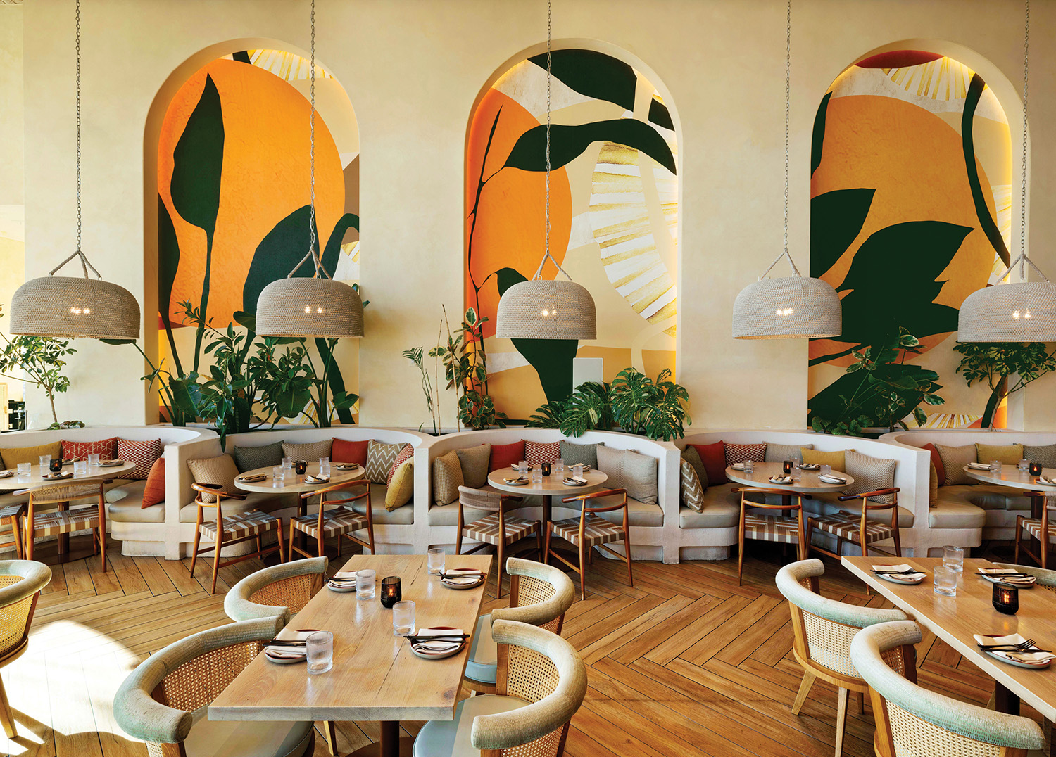 A restaurant with a large mural of tropical leaves.