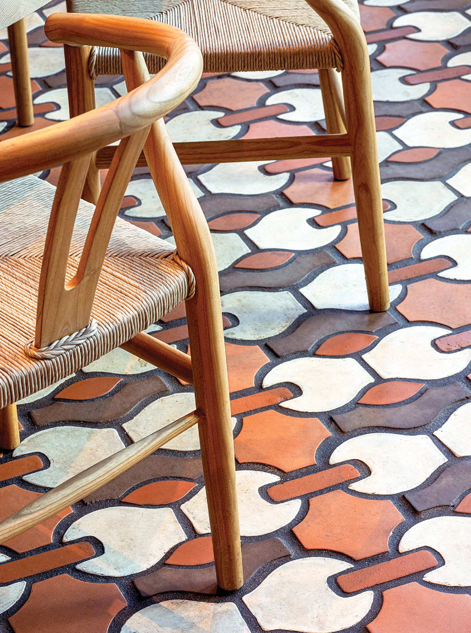 A chair with a wooden seat on a tiled floor.
