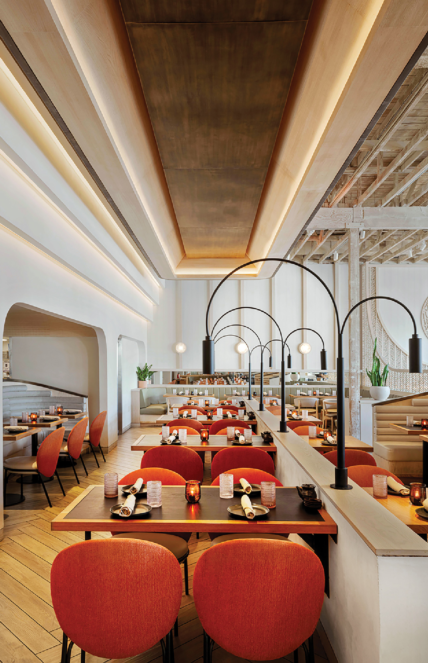 A restaurant with a long table and red chairs.