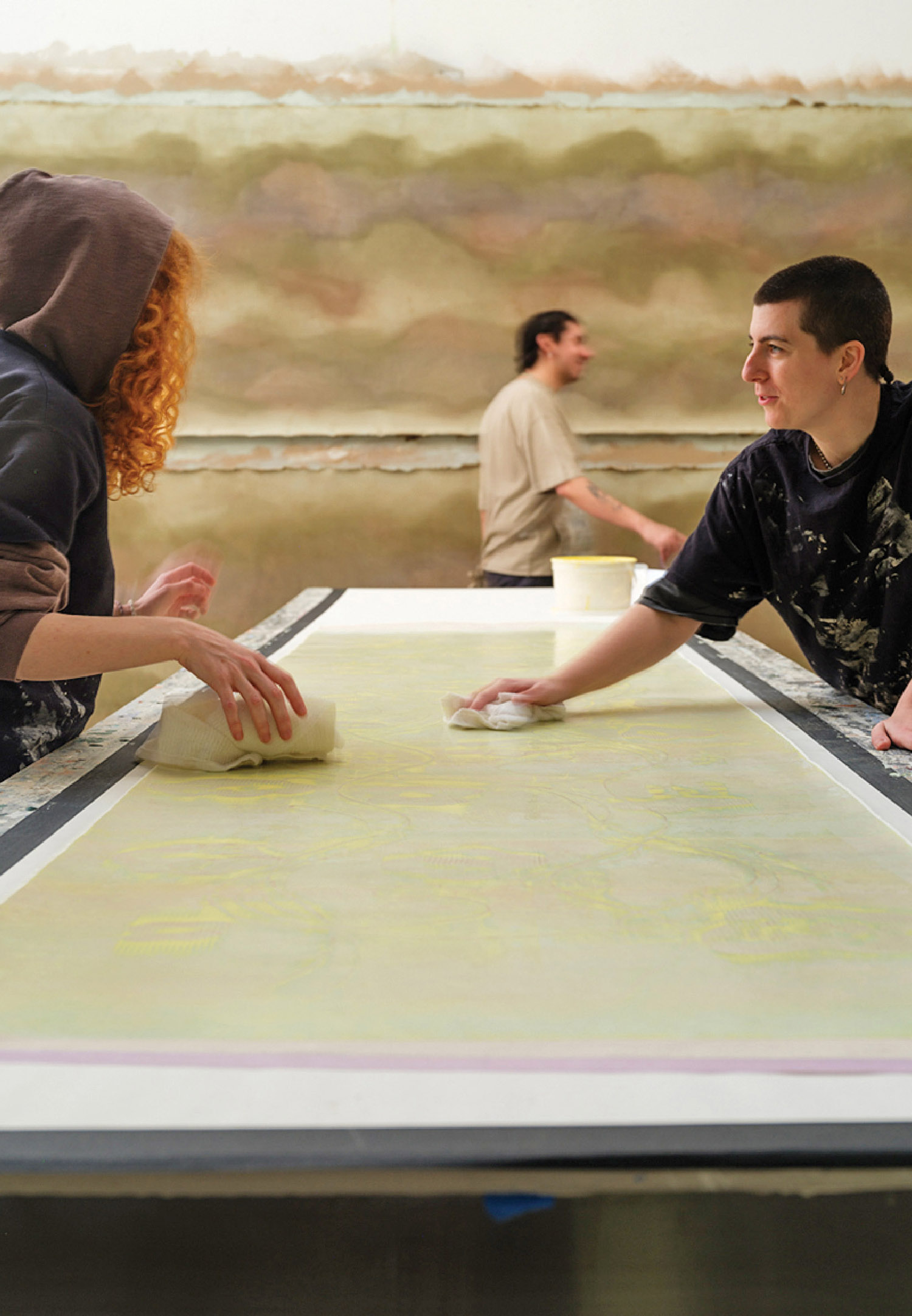 A woman and a man are working on a painting.