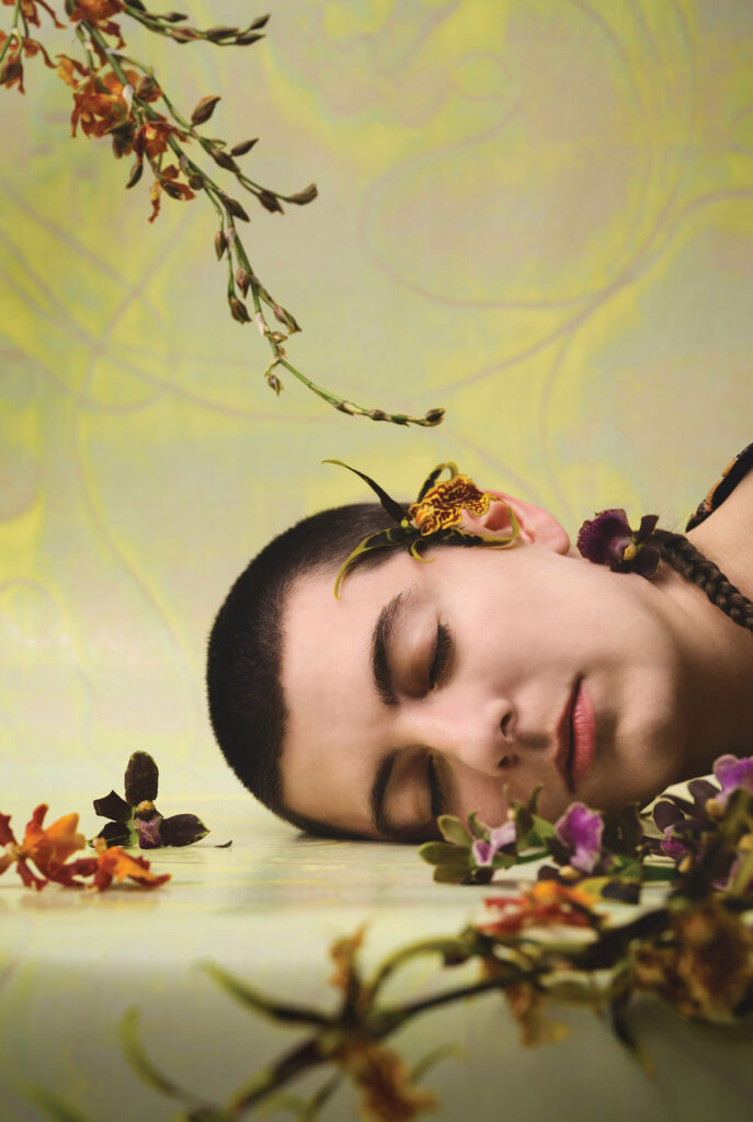 A woman laying down on a table with flowers.