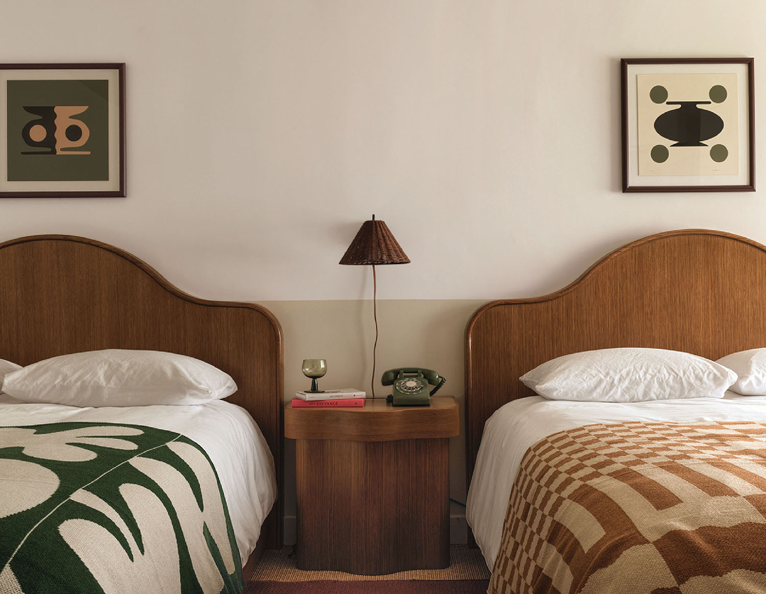 Two beds in a bedroom with a lamp on the side.