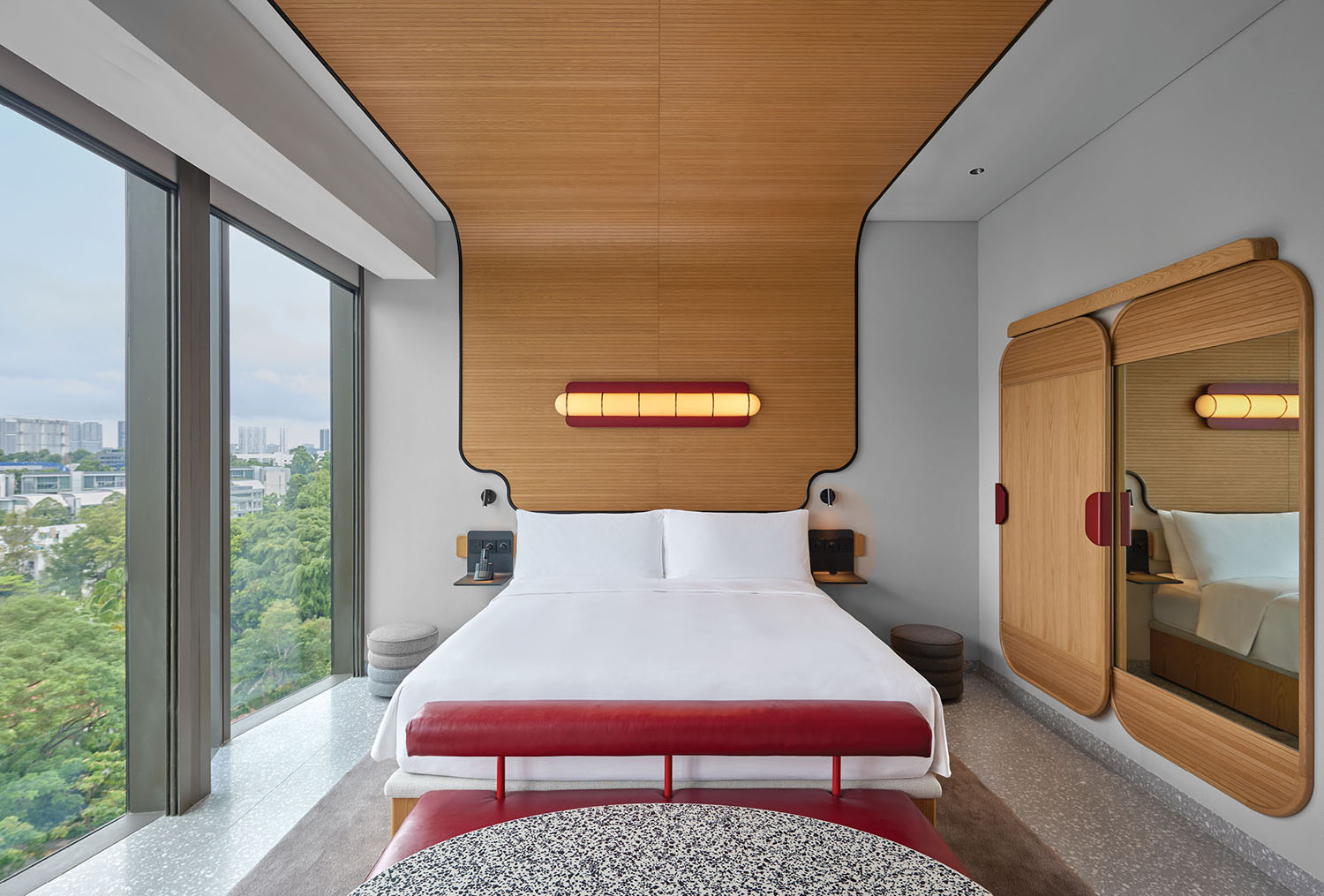 A bedroom with a bed and a red ottoman.