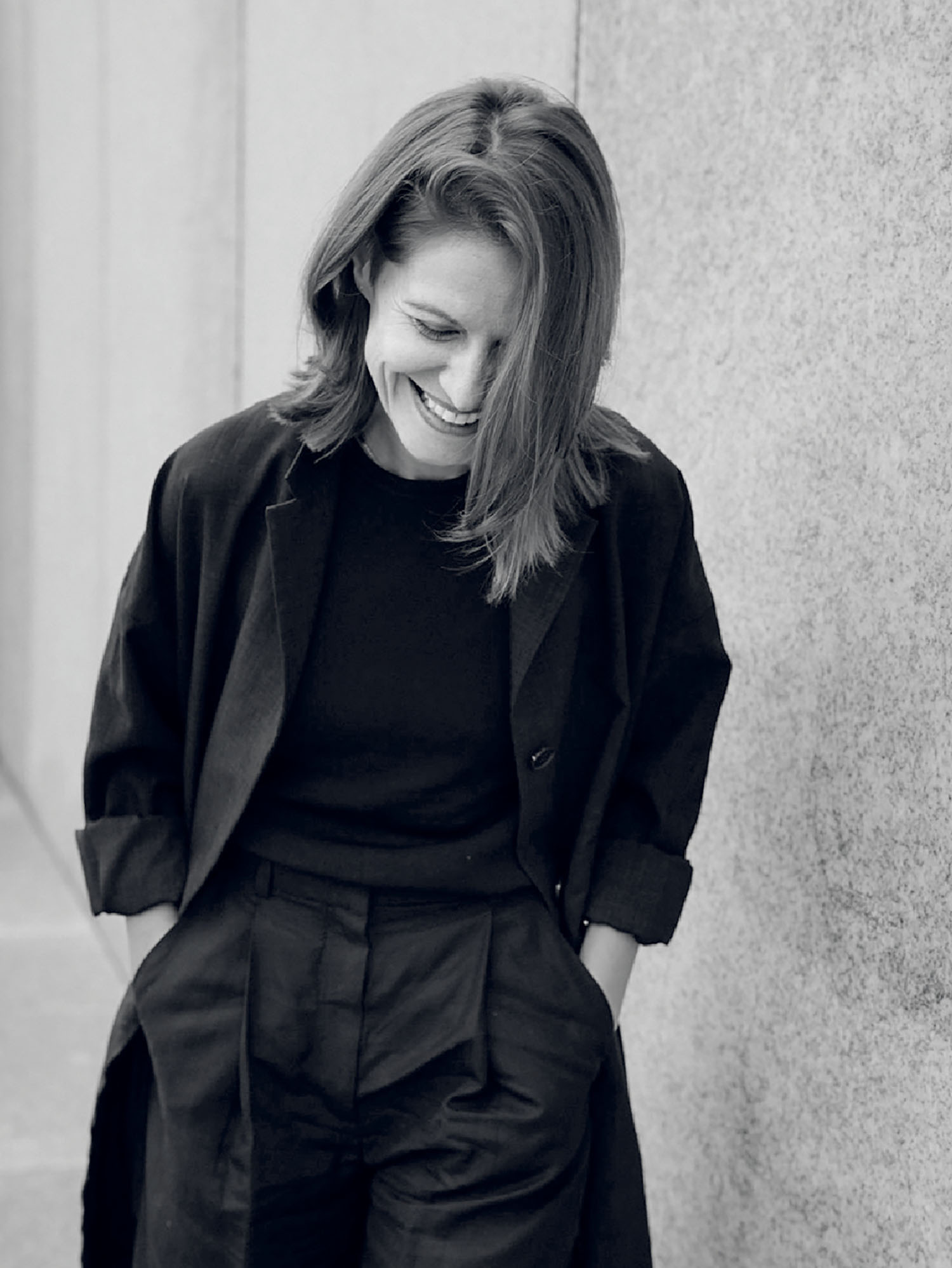 A woman in black and white standing next to a wall.