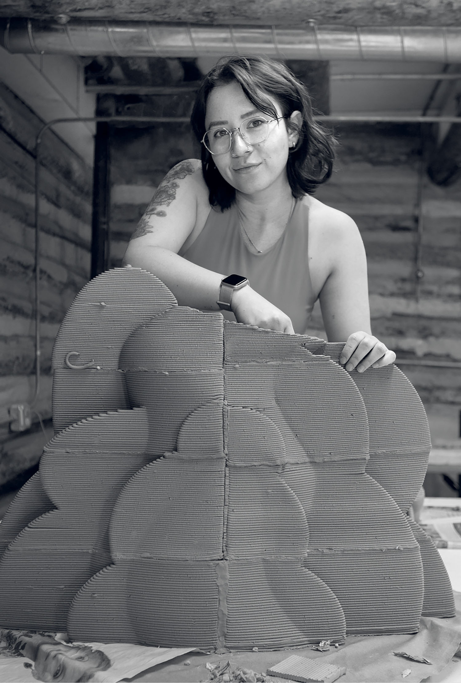 A woman is sitting in front of a cardboard sculpture.