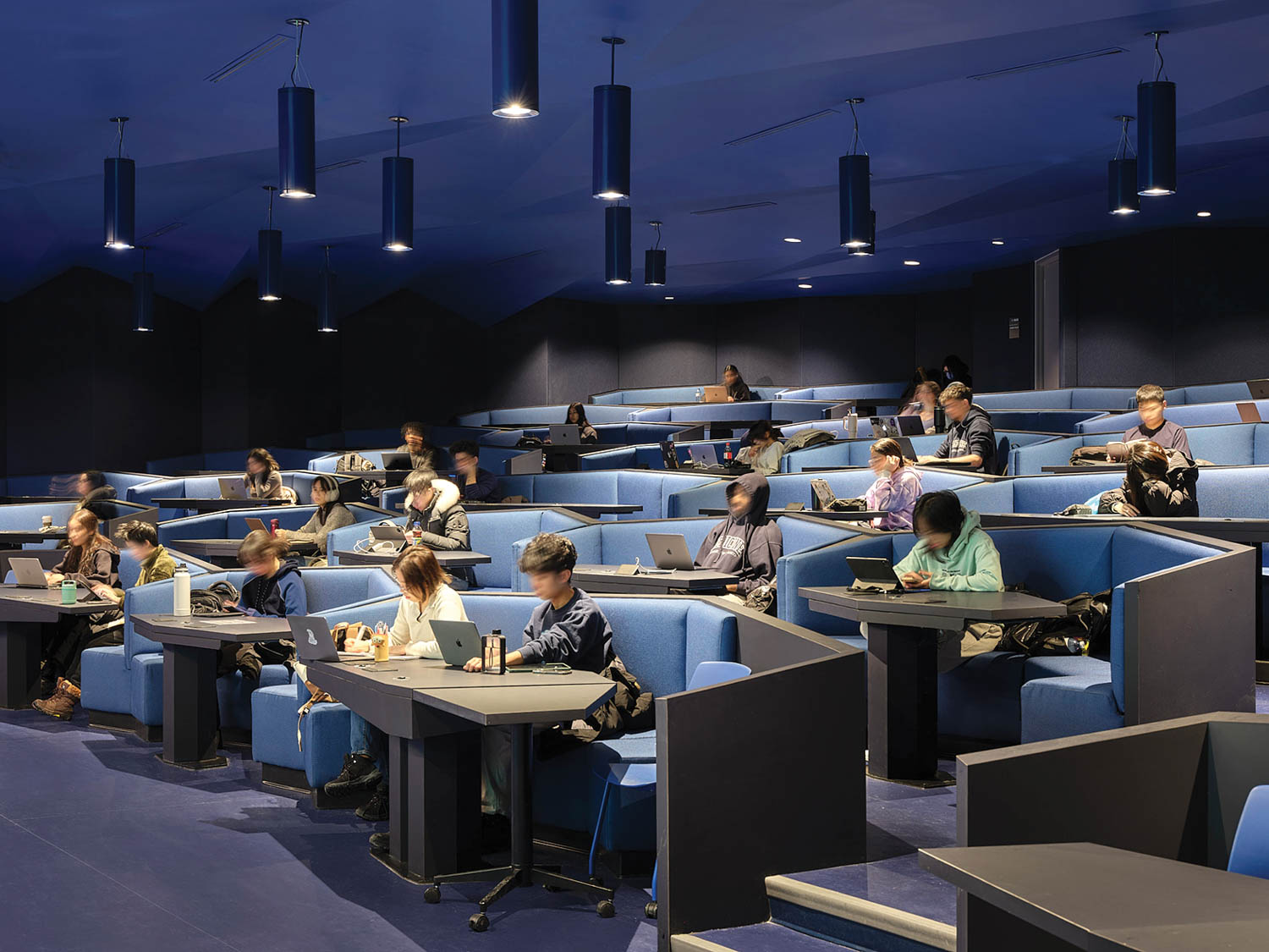 multiple students sitting inside an all blue room with blue seats