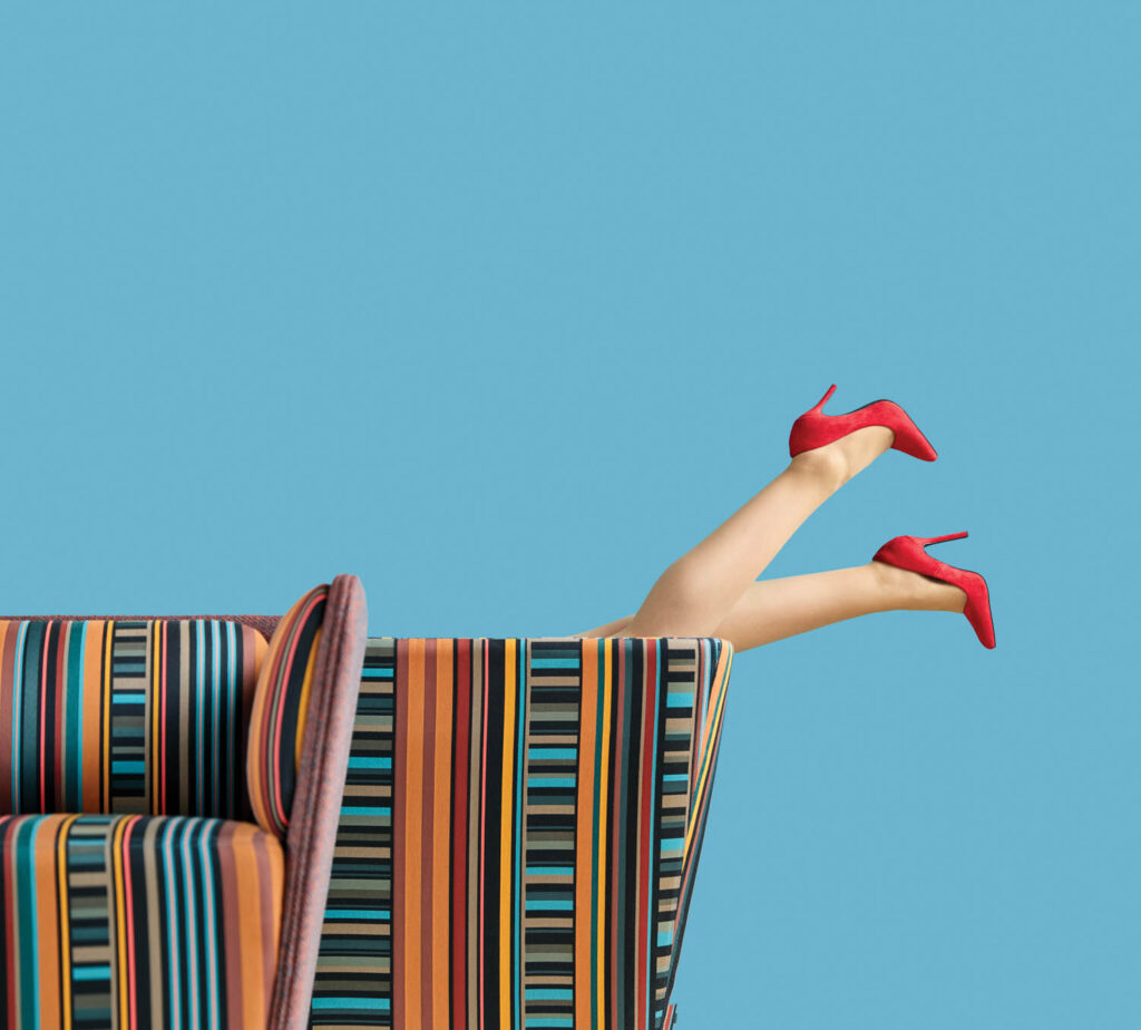 image of someone's legs sticking out of couch with red heels