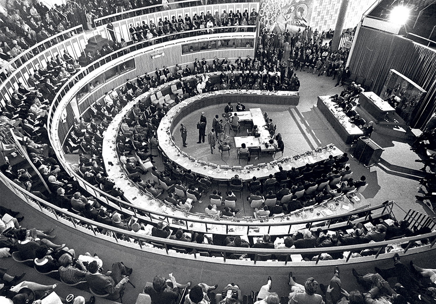 A large circular room with a stage and a crowd.