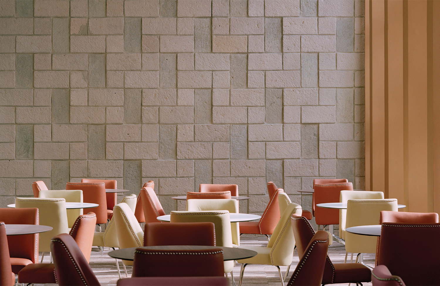 A room with a wall of bricks and chairs.