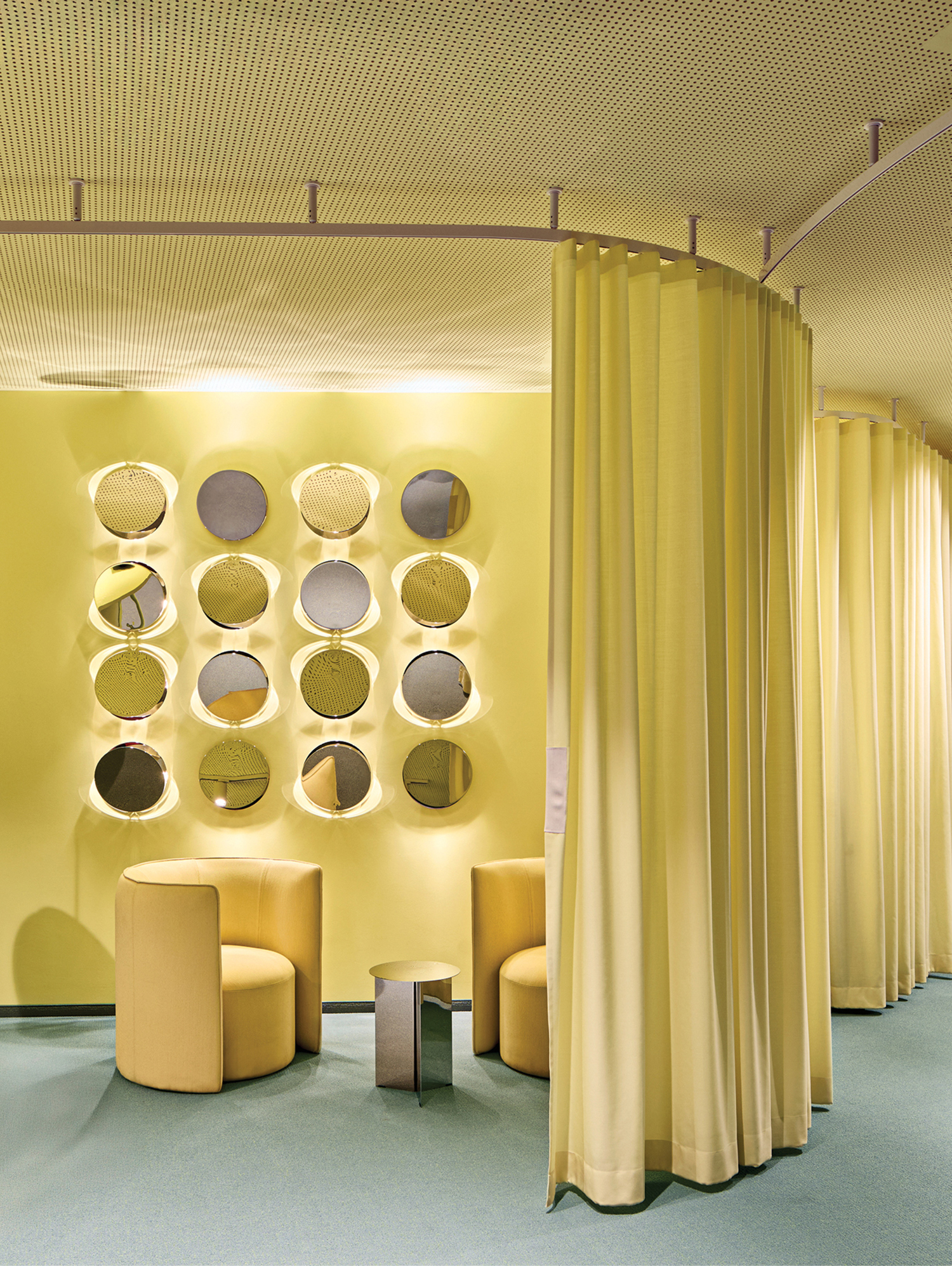 A room with a yellow wall and a round mirror.