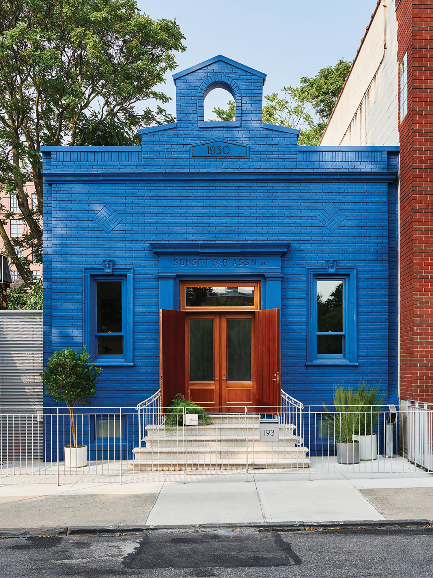 A blue building with a red door and a white fence.