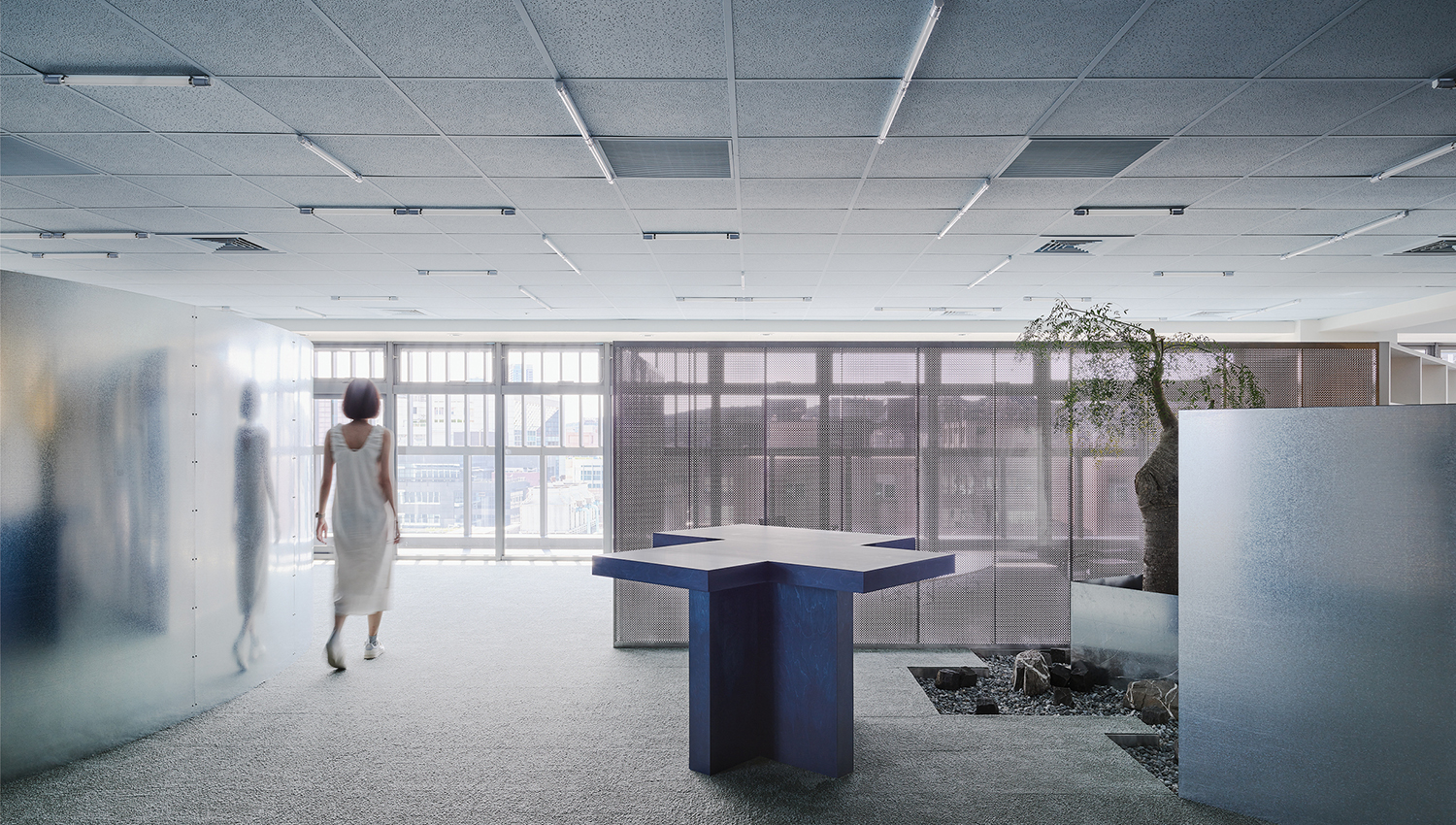 A woman walking through a room with a blue table.