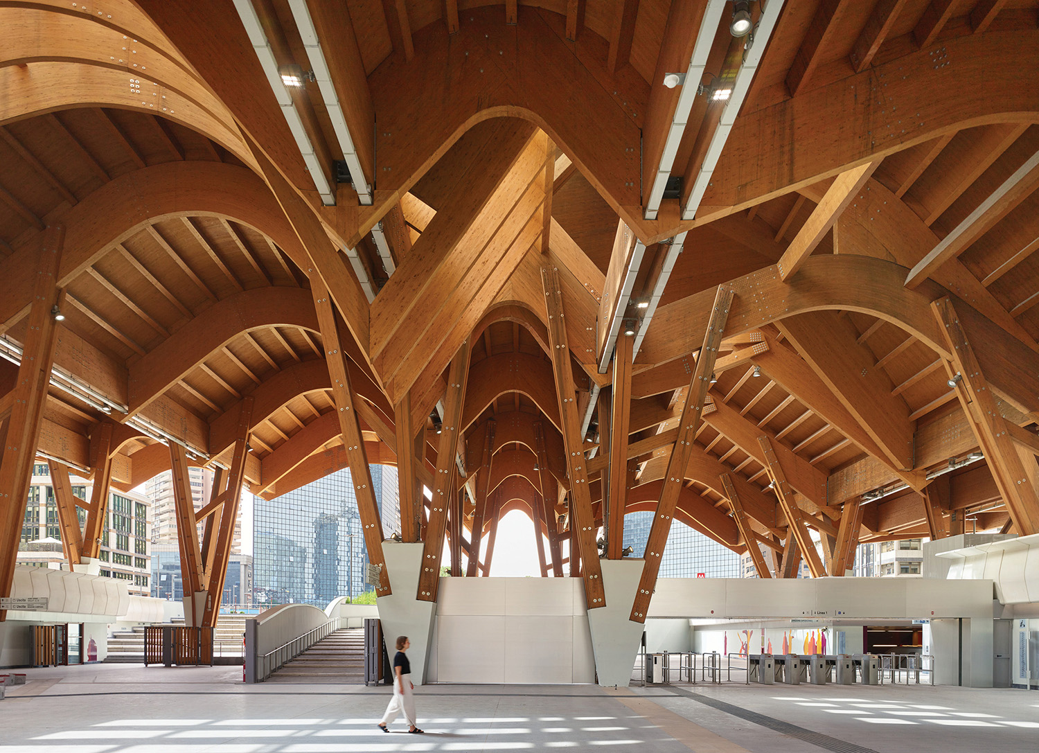 A person walking in a large building with wooden beams.