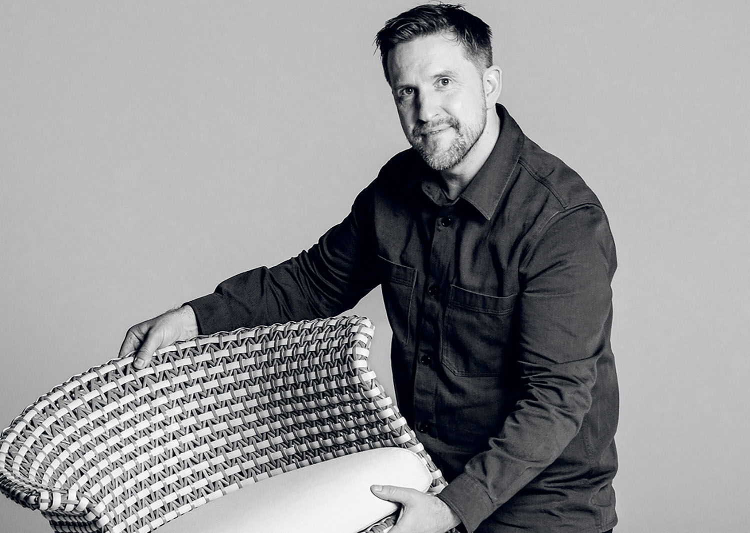 A man sitting on a chair with a pillow.