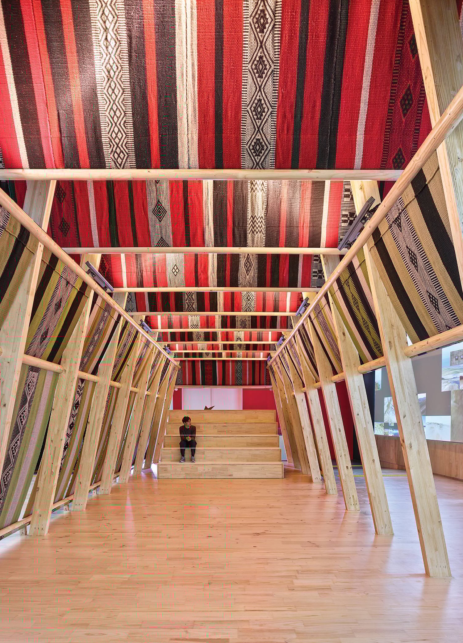 A room with a wooden floor and a red and black rug
