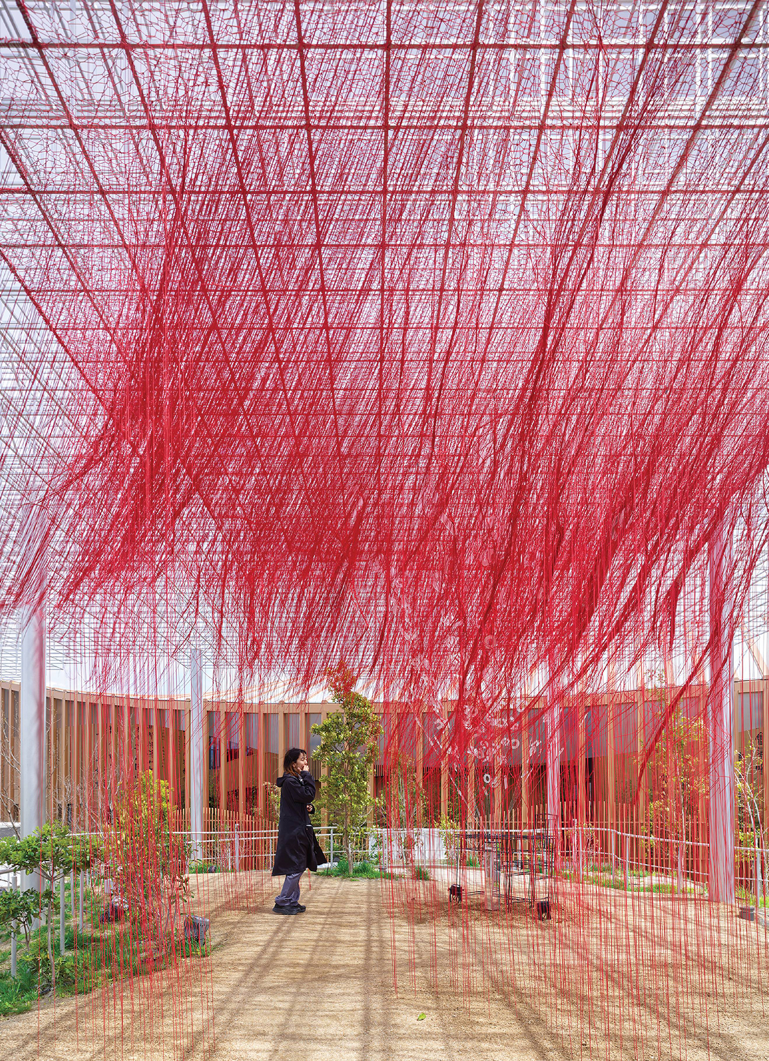 A red sculpture in a courtyard with a person standing under it