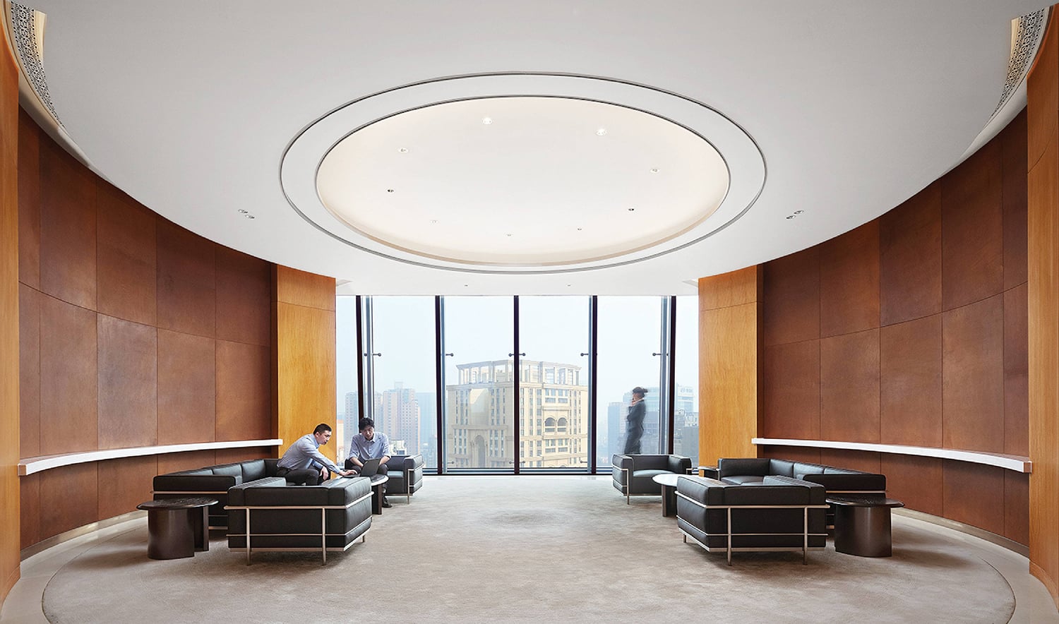 A man sitting in a large room with a view of the city.