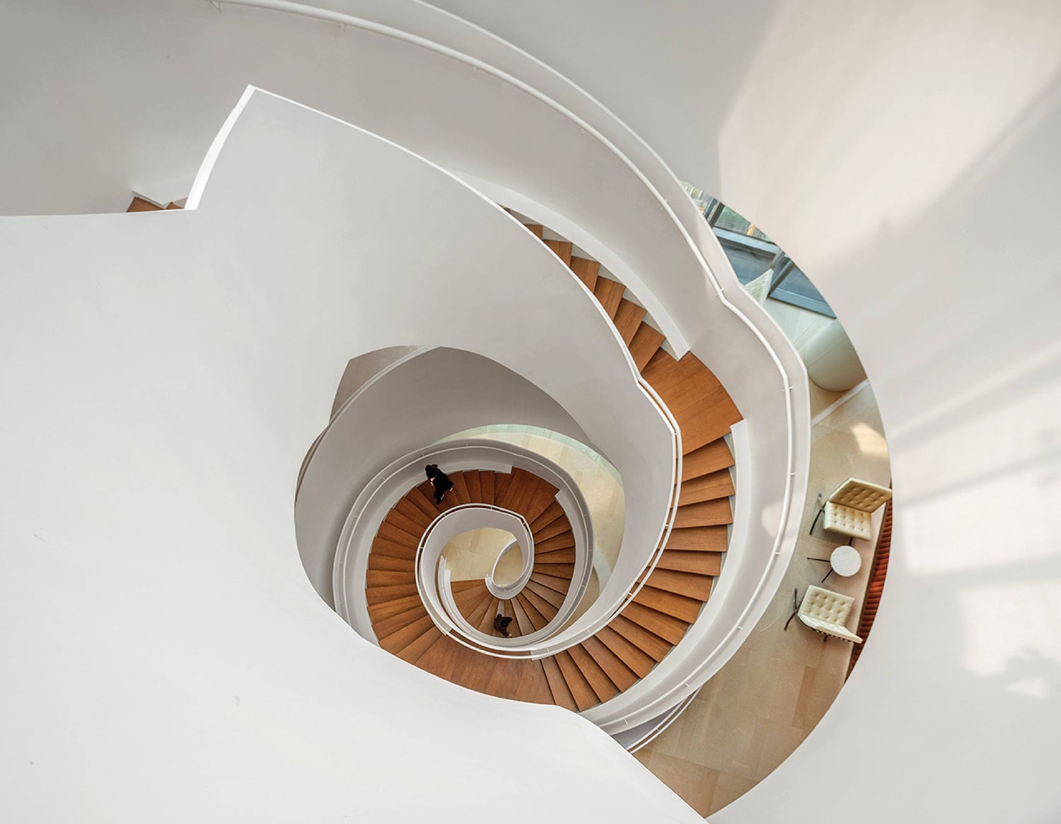 A spiral staircase with a man walking up it.