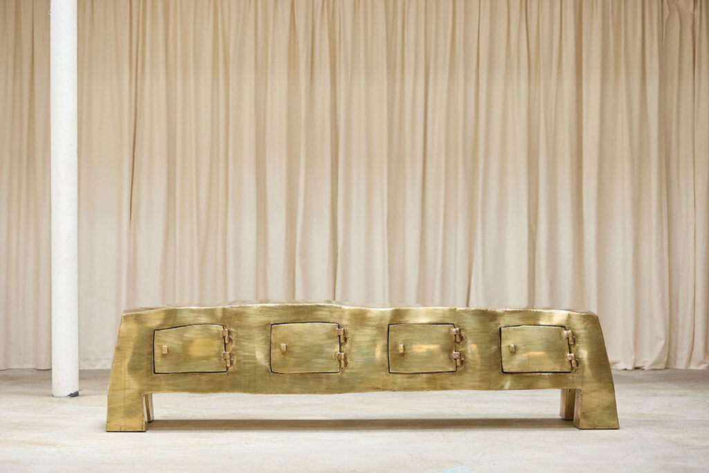 A gold bench with a white curtain behind it