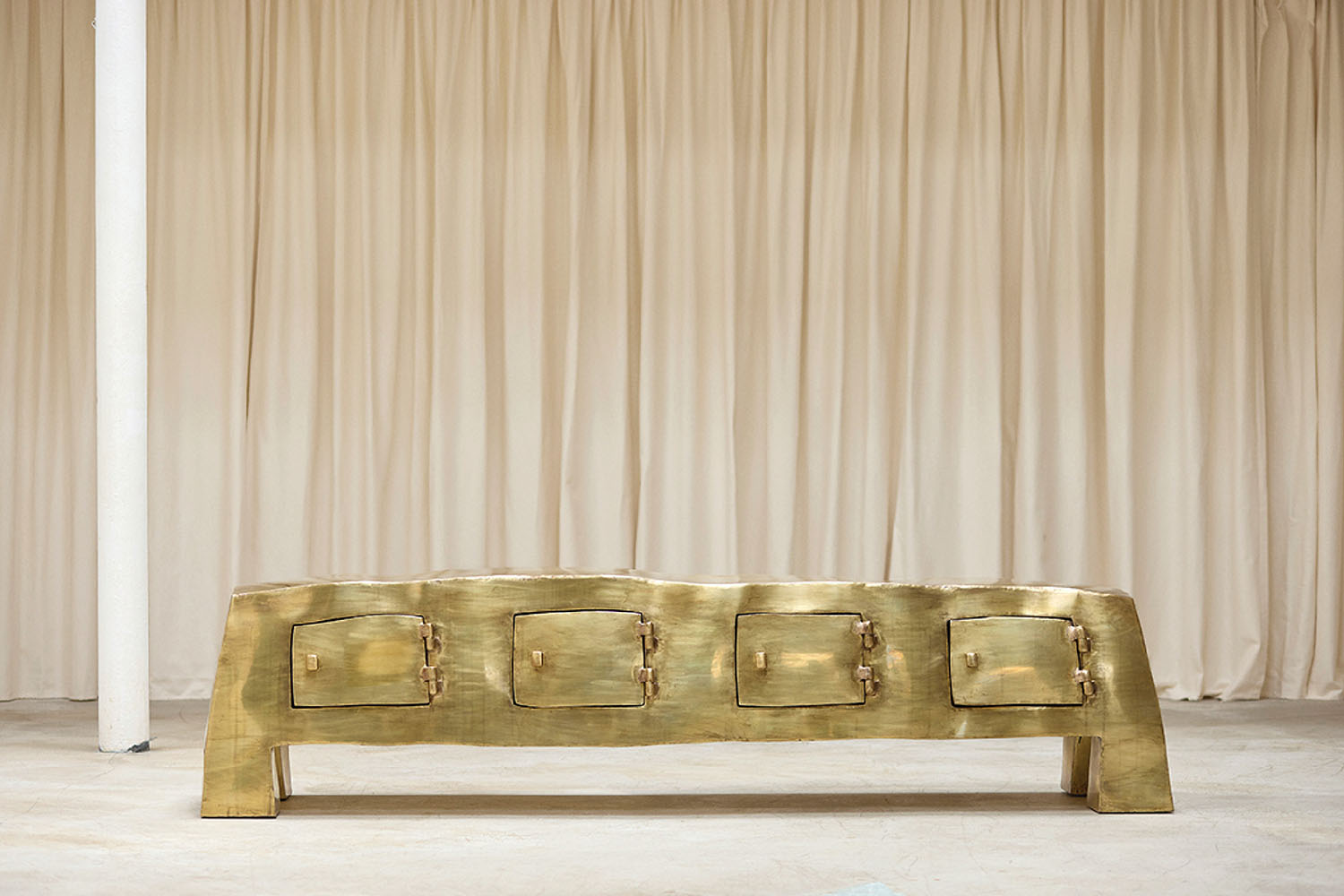 A gold bench with a white curtain behind it