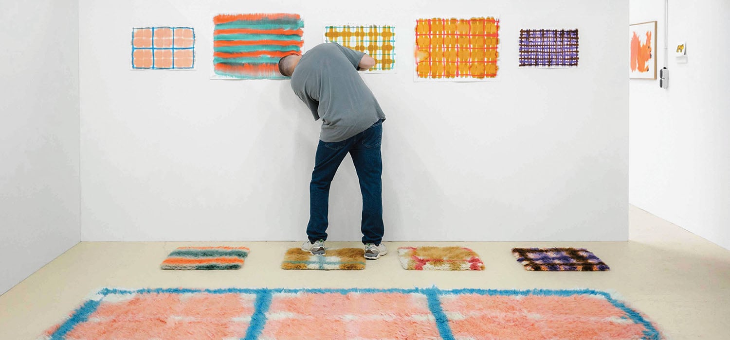 A man standing in front of a wall with a painting on it