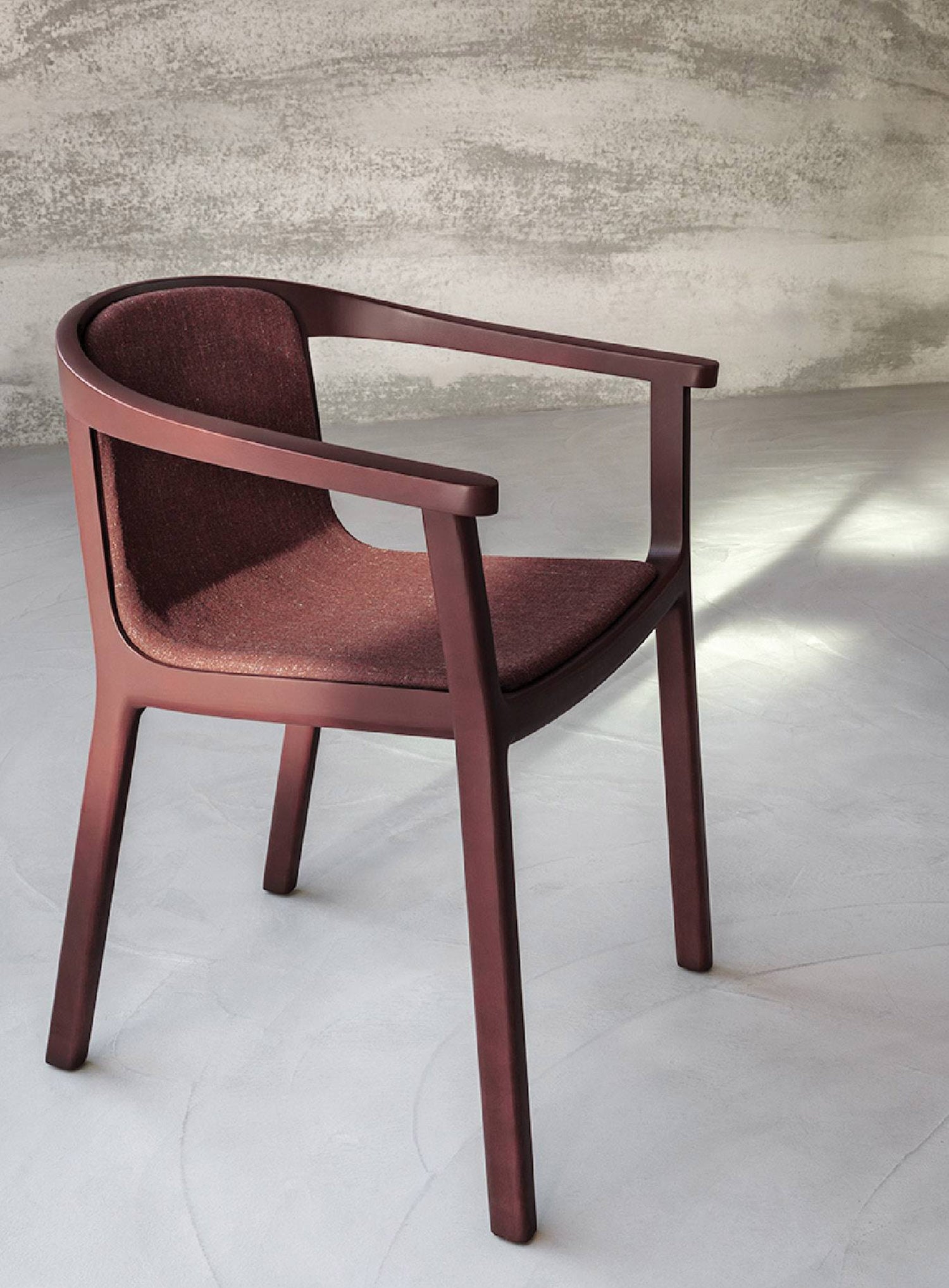 A red chair with a wooden frame and armrest.