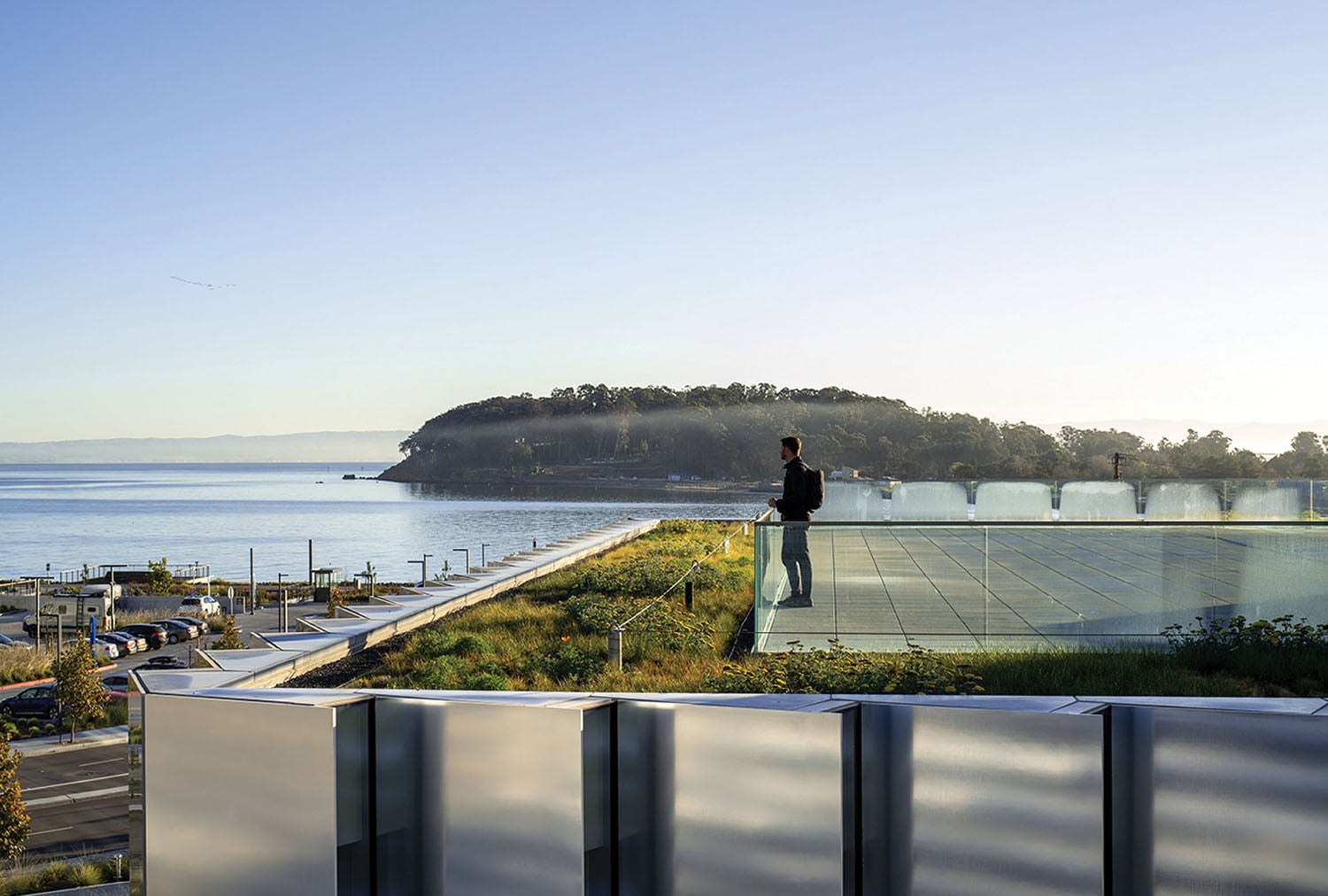 A man standing on a balcony overlooking a body of water