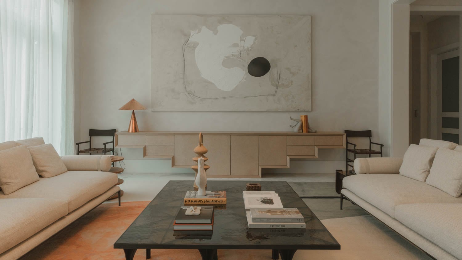 living room with white couches and black coffee table with books