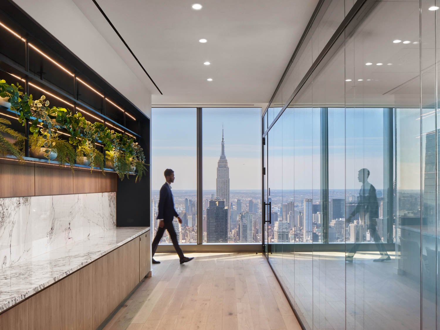 man walking through hallway with glass windows