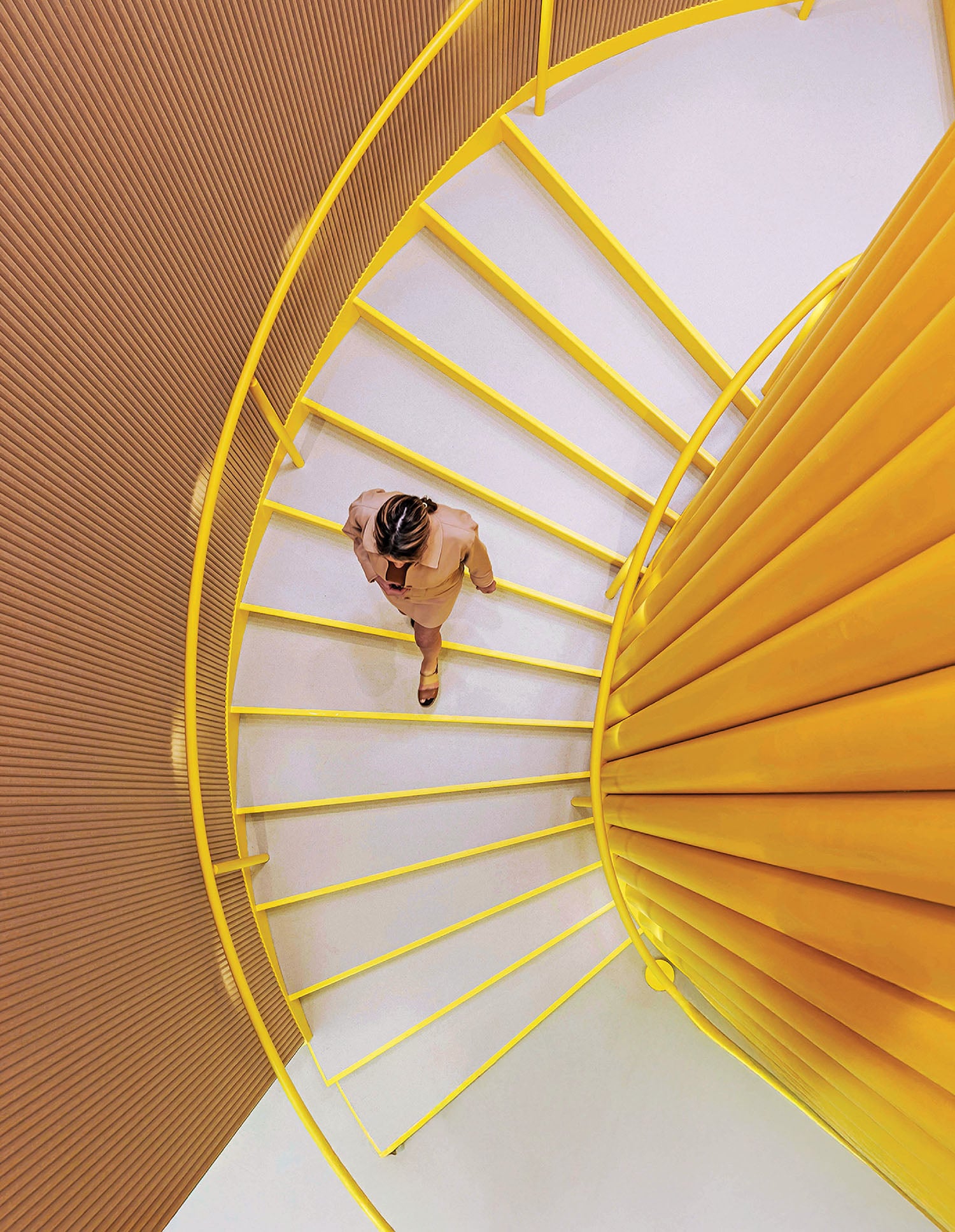 A woman is walking up a spiral staircase.