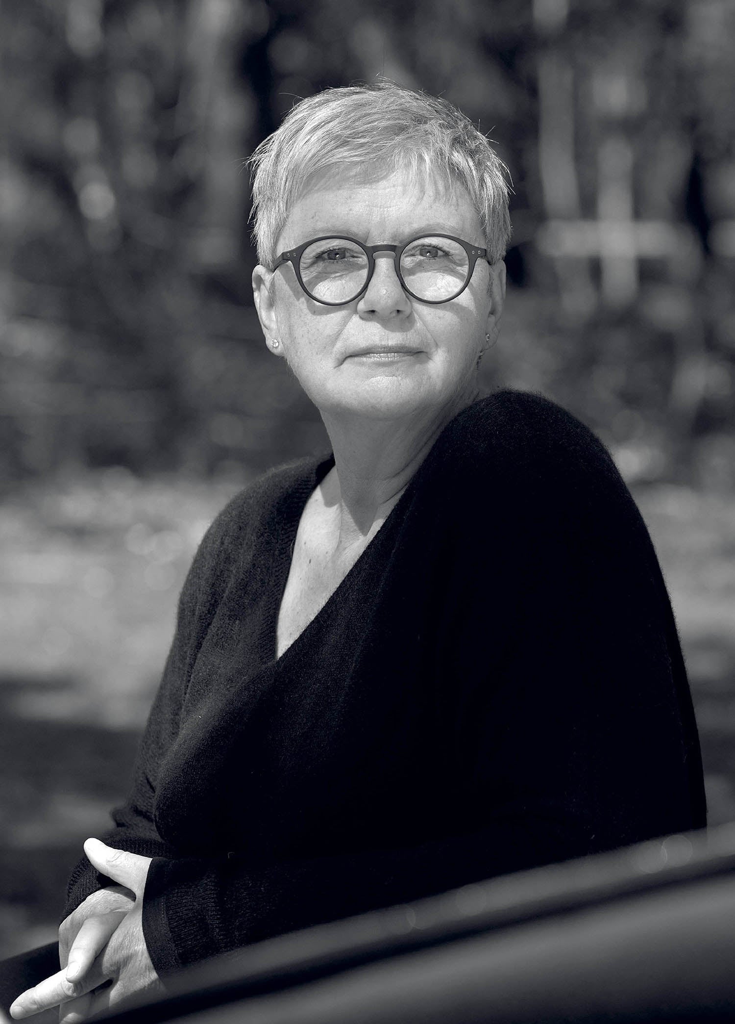 A woman with glasses is sitting on a bench.