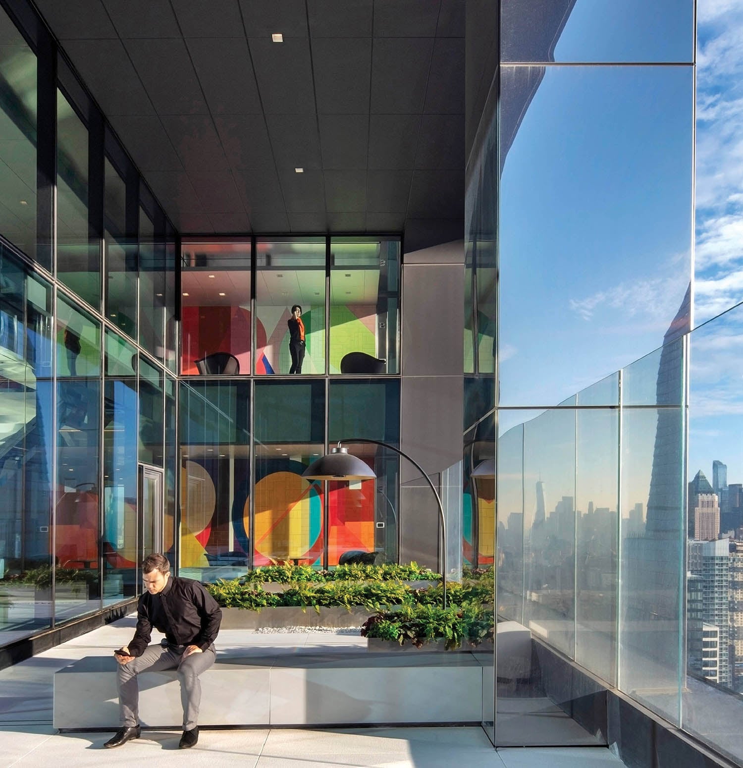 A man sitting on a bench in front of a glass wall.