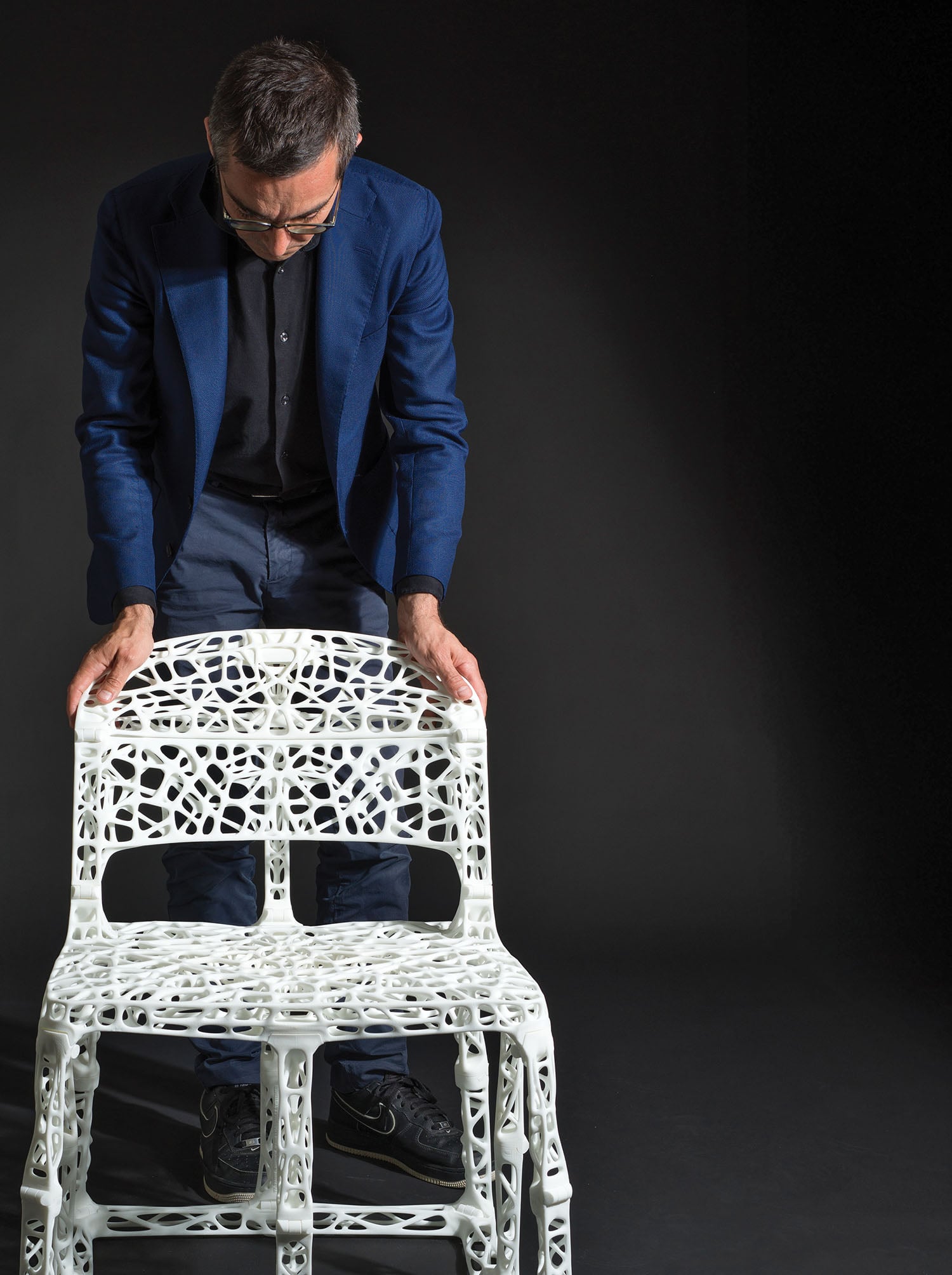 A man in a blue suit is sitting on a white chair.