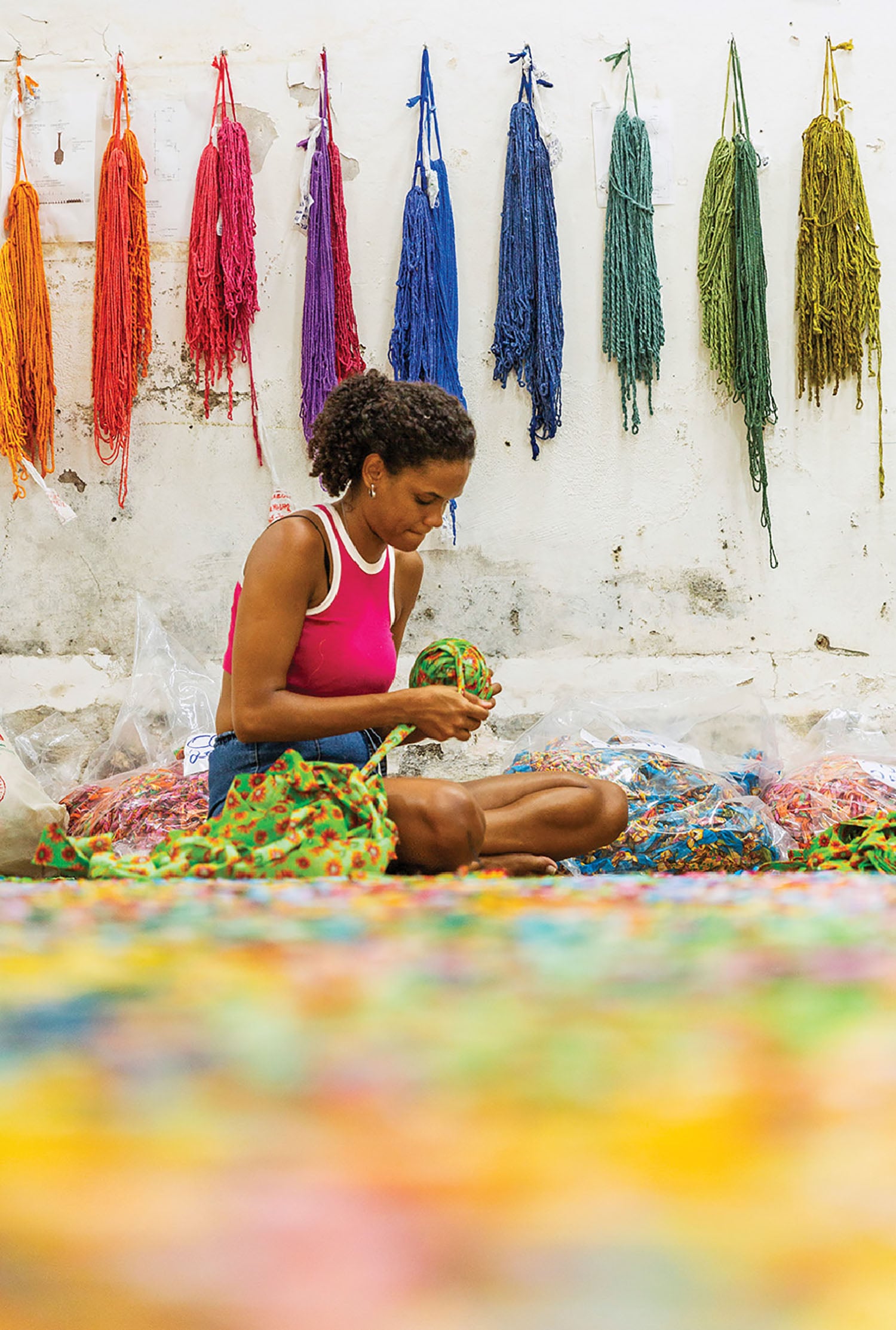 A woman sitting on the ground with a bunch of yarn.