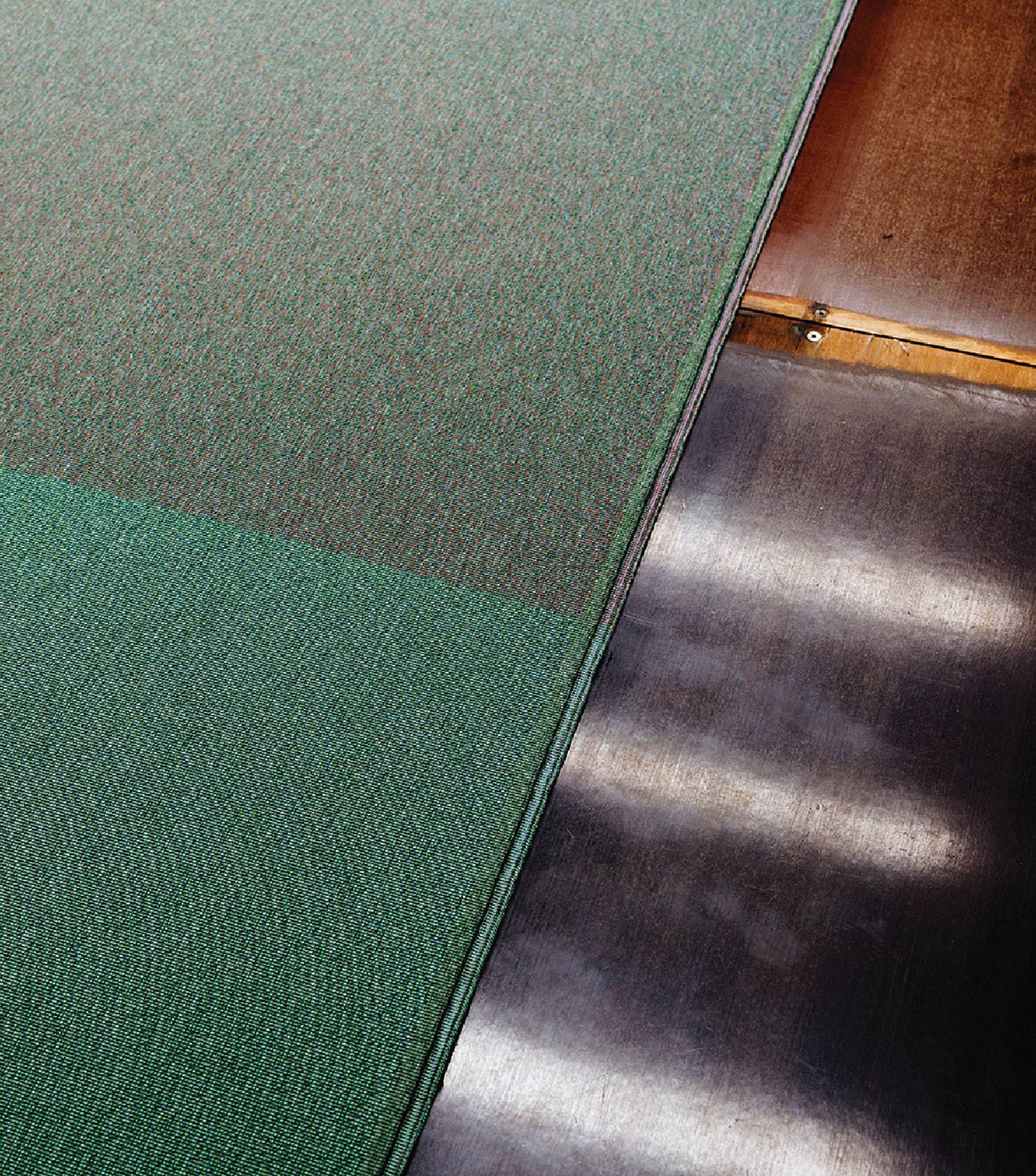 A green rug on a wooden floor.