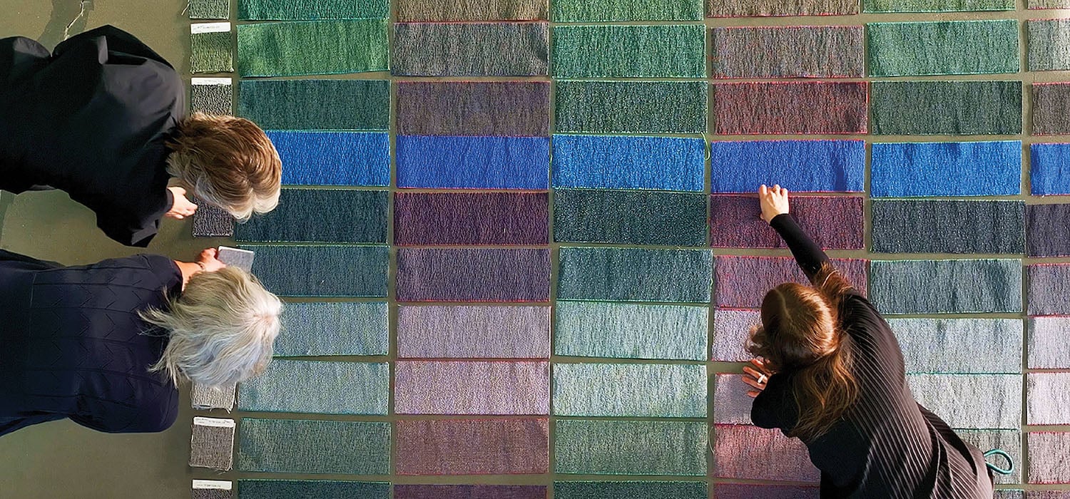 Two women looking at a wall with a piece of art on it.